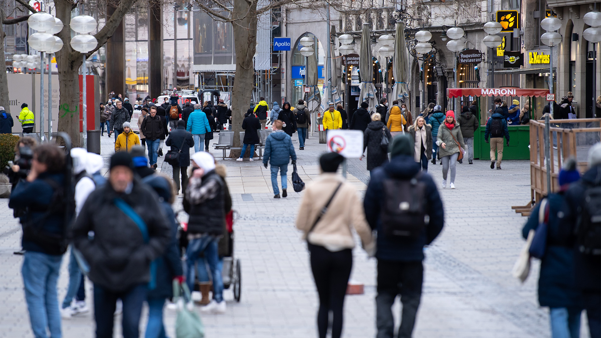 Passanten laufen durch eine Fußgängerzone in München. | dpa