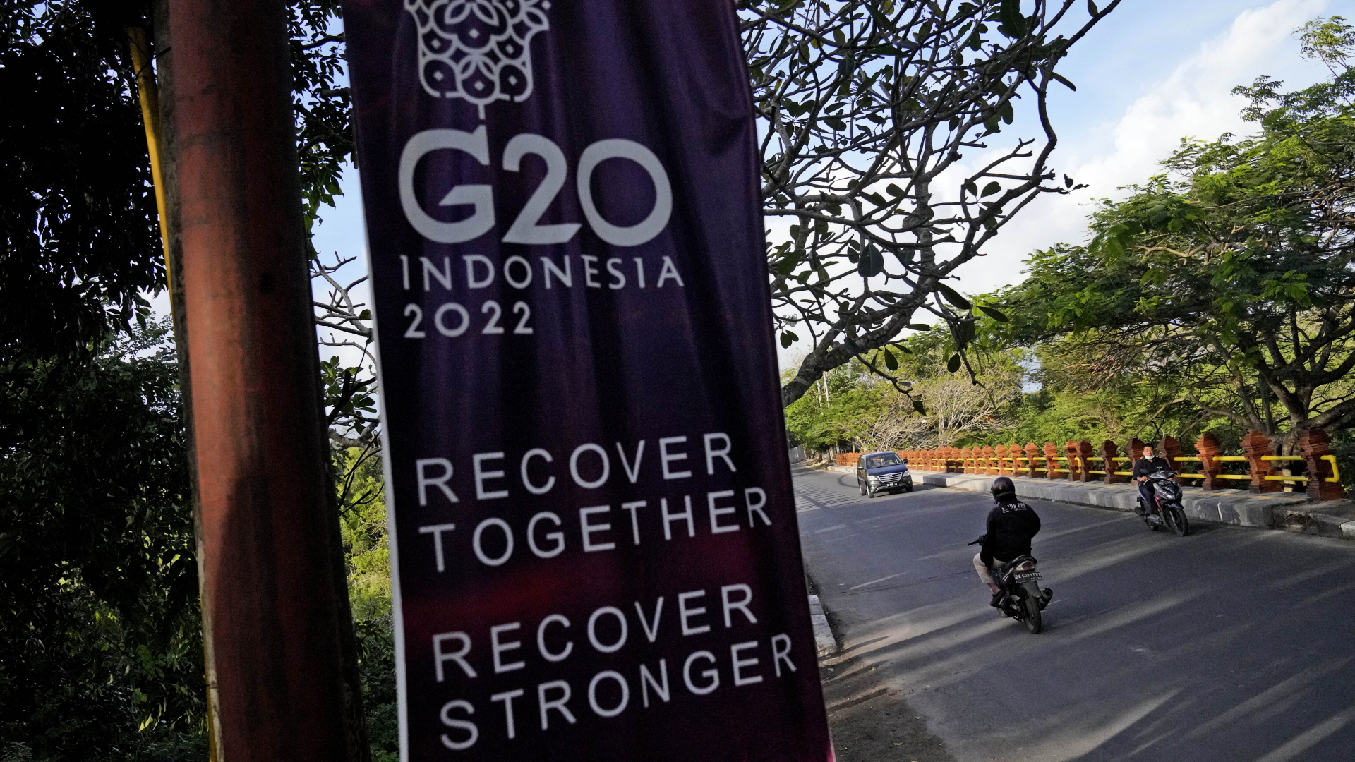 Autofahrer fahren an einem G20-Banner auf Bali vorbei.
