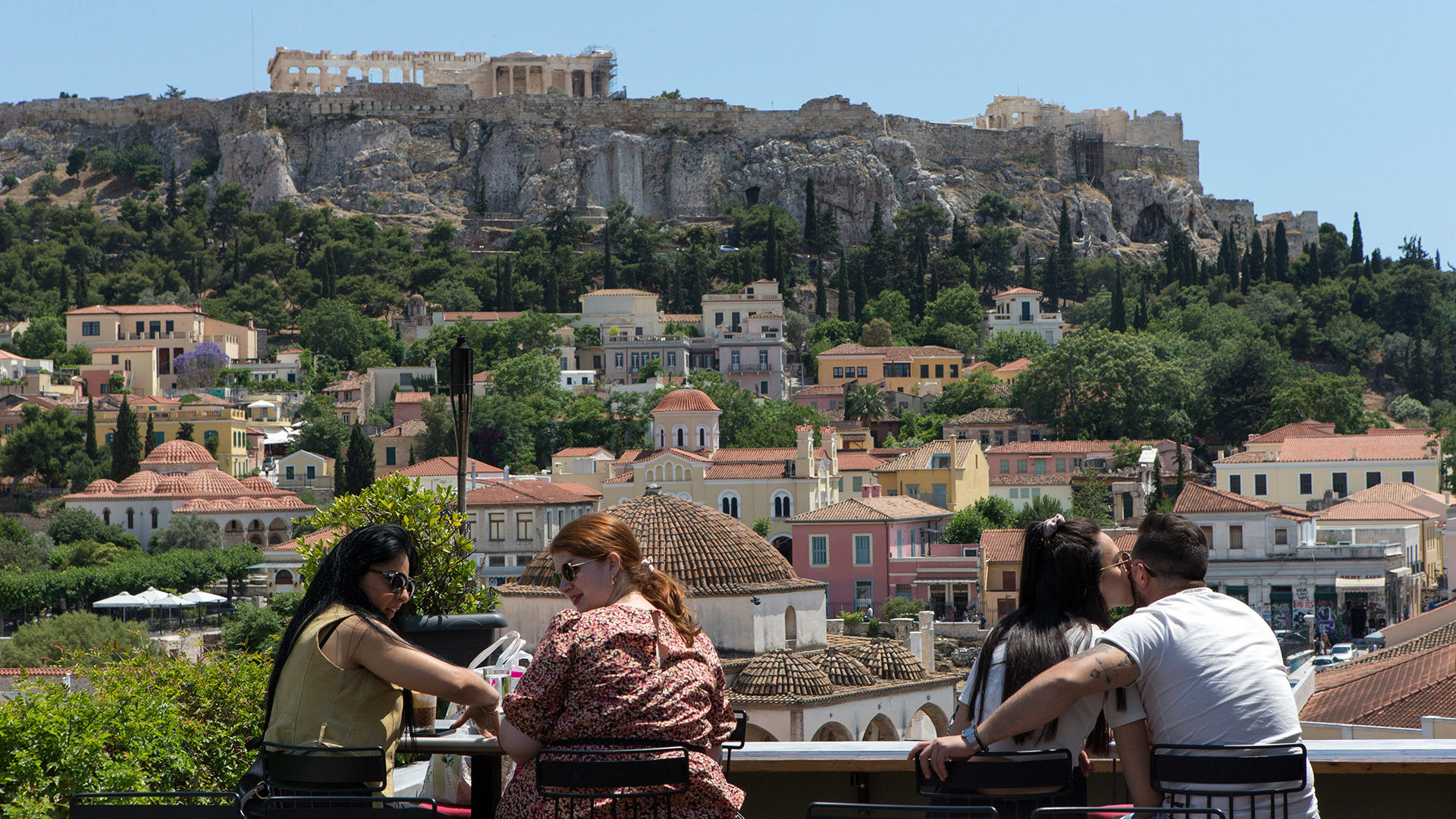 Gäste sitzen in einem Café im Stadtteil Monastiraki mit der Akropolis im Hintergrund.  | dpa