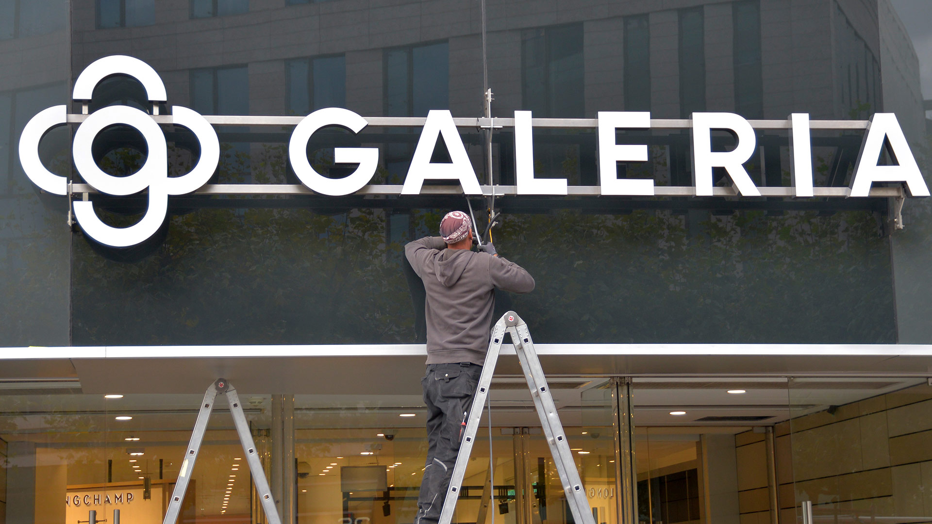 Ein Arbeiter montiert das neue Firmenschild Galeria an die Fassade des Kaufhaus Galeria Kaufhof, Frankfurt/Main