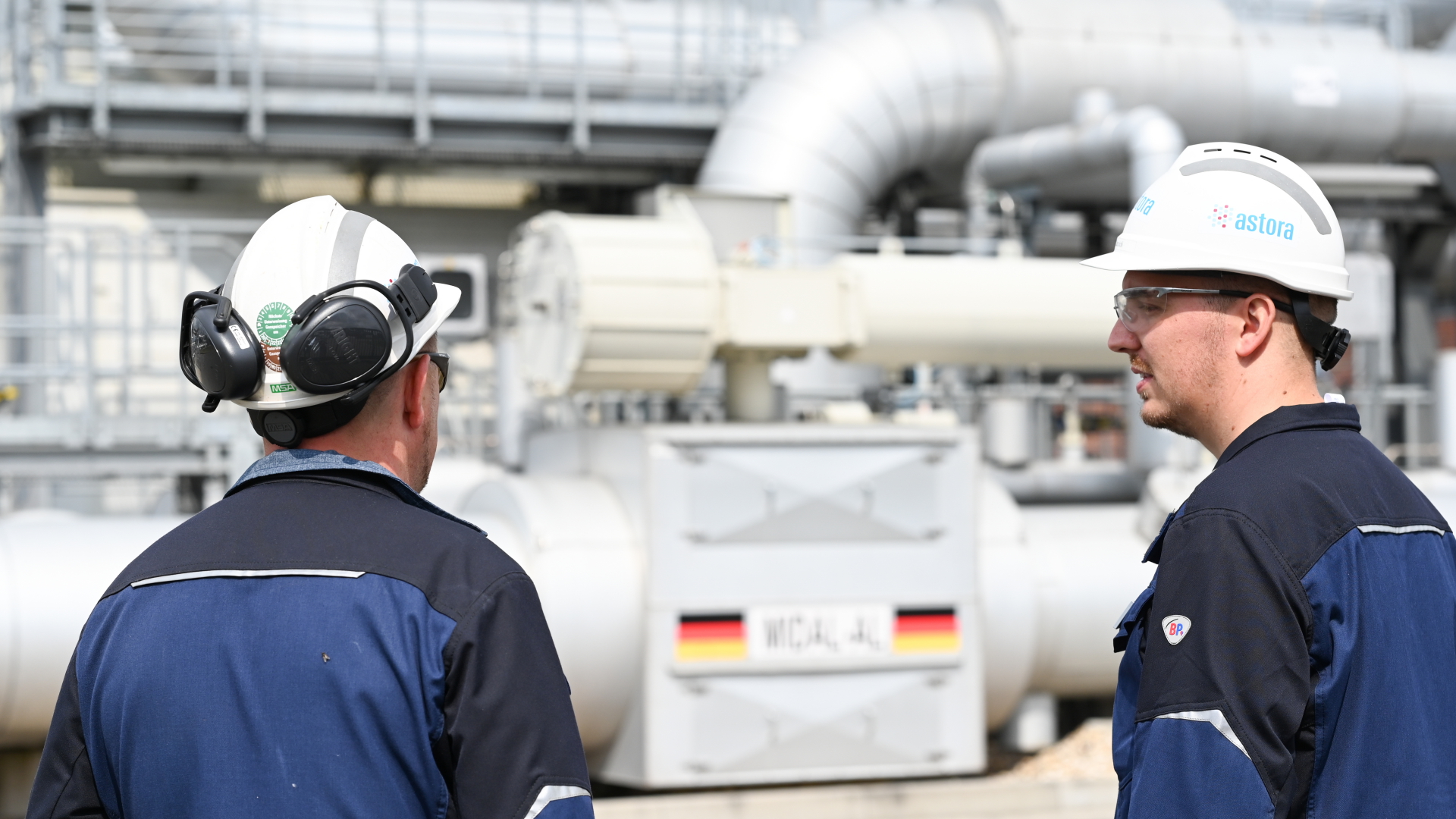 Zwei Mitarbeiter stehen auf dem Gelände des Astora Gasspeichers in Jemgum. Der Speicher ist einer der größten Erdgasspeicherbetreiber in Europa. | dpa