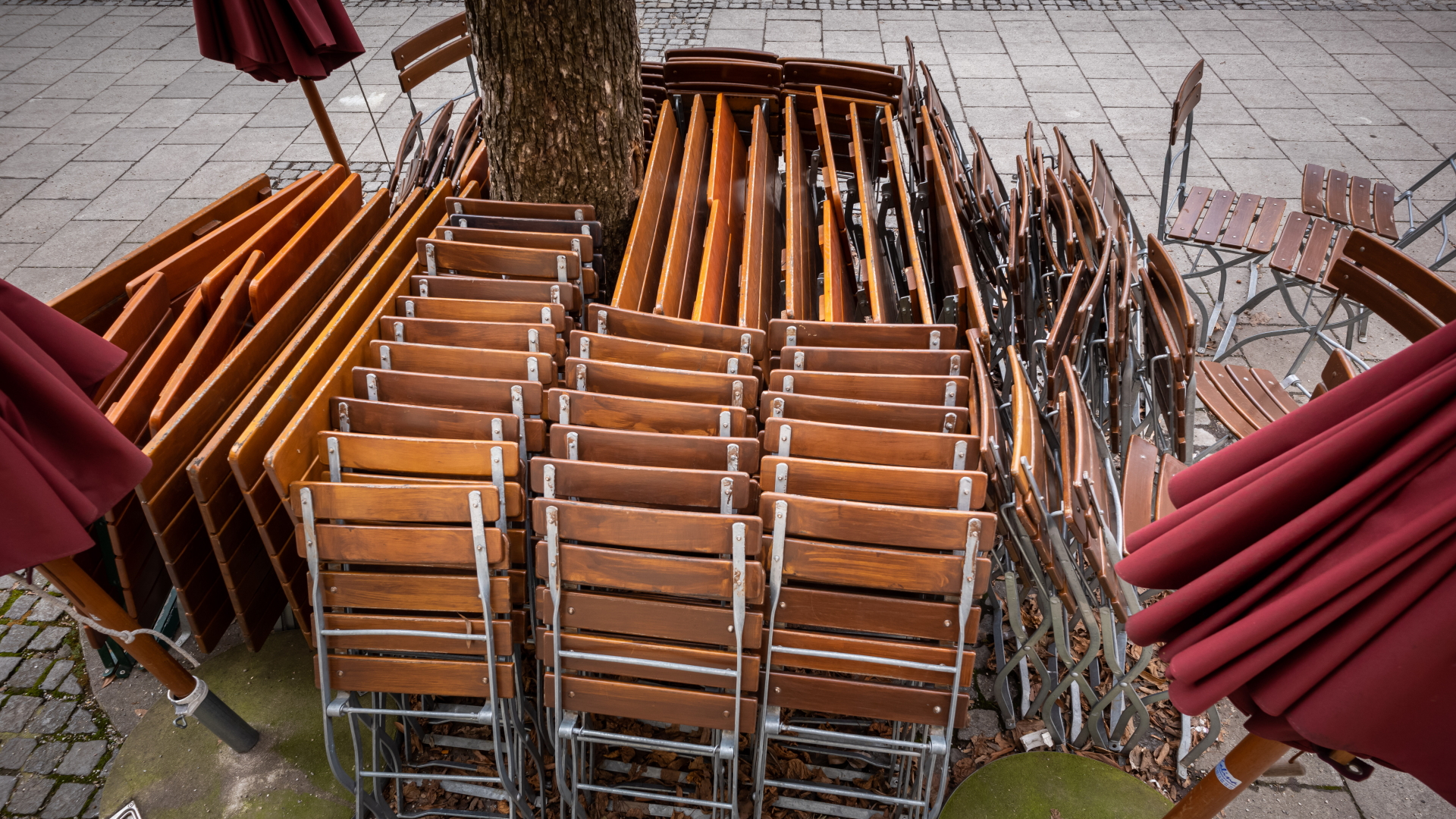  Zusammengestellte Tische und Stühle stehen vor einem geschlossenen Restaurant in München-Haidhausen.