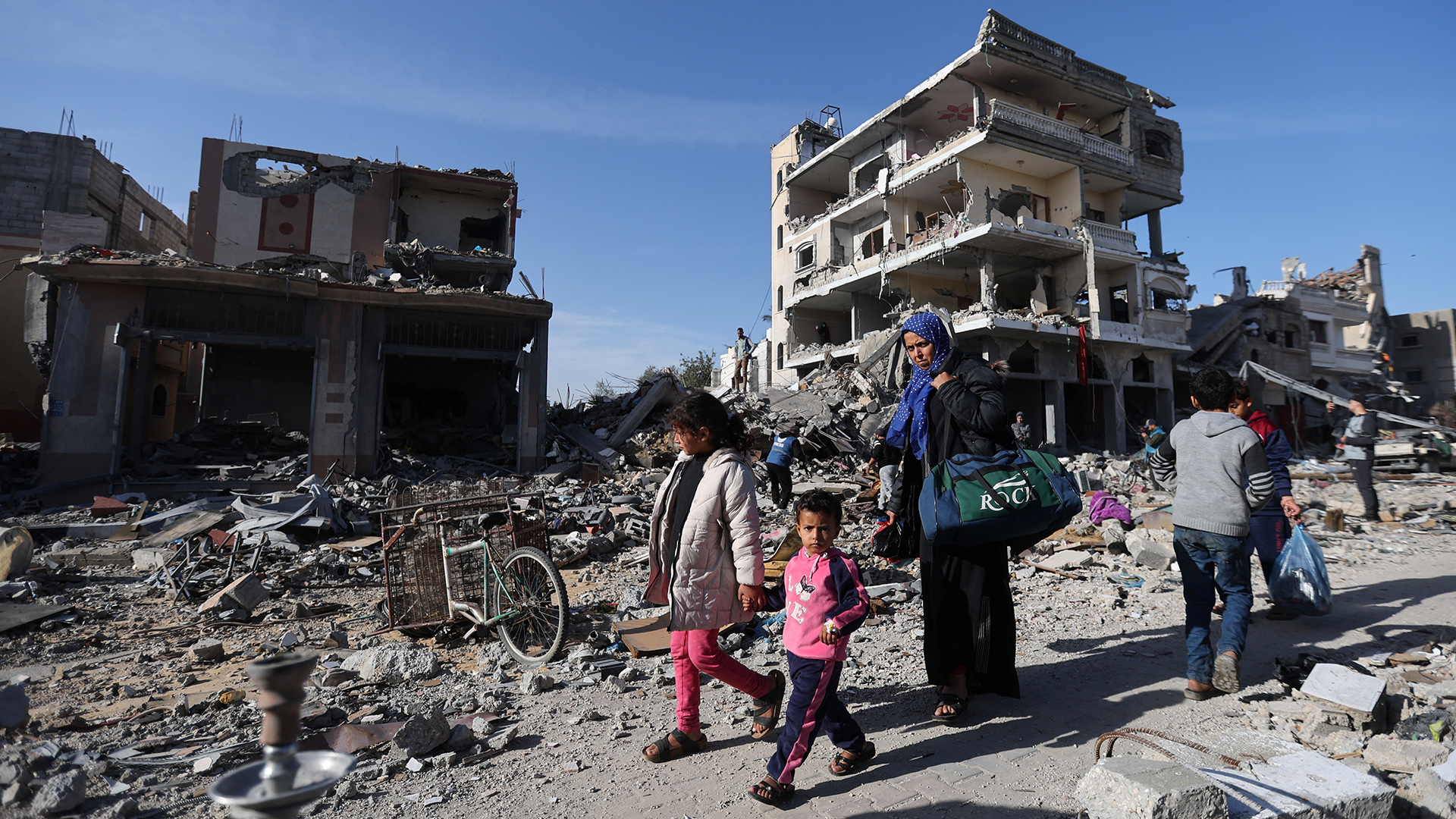 Vertriebene Palästinenser kehren in ihre Häuser zurück, während sie an einem zerstörten Haus in Khan Yunis vorbeigehen.
