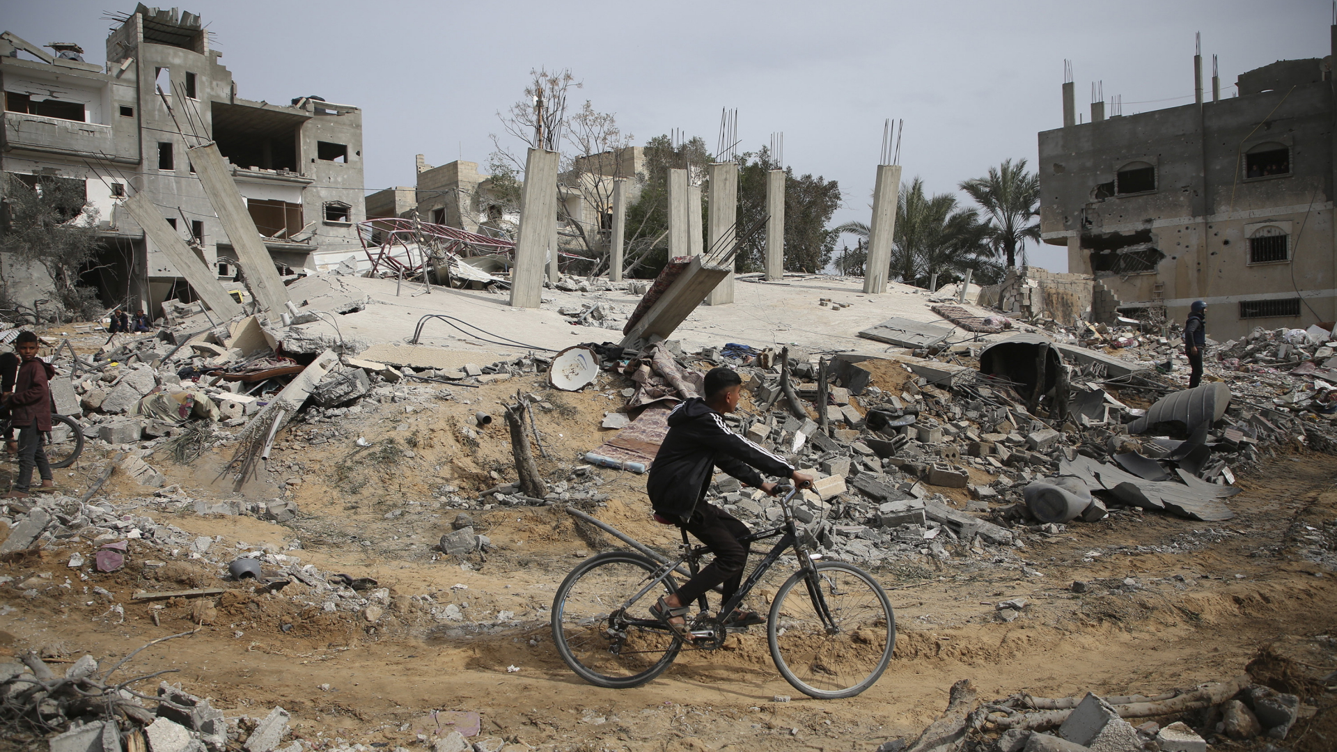 Ein Palästinenser fährt auf dem Fahrrad zwischen zerstörten Gebäuden im Gazastreifen