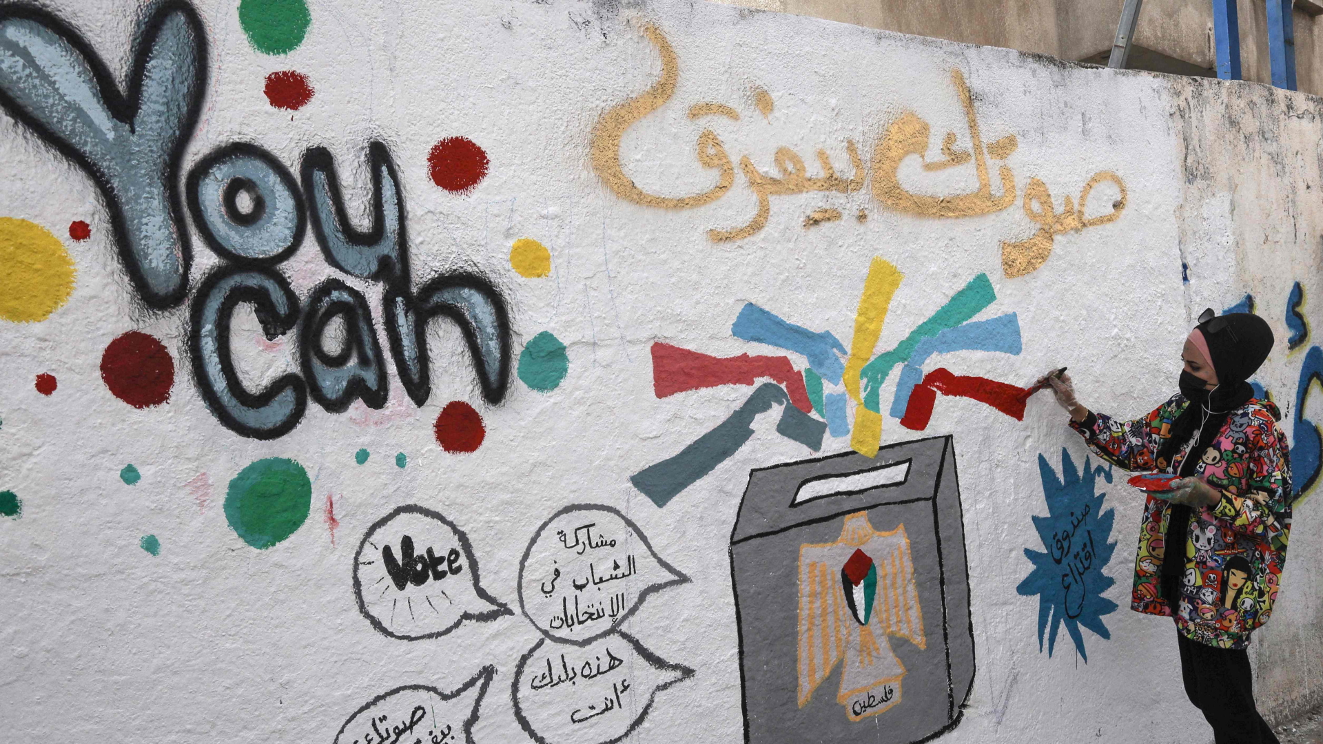 Eine Künstlerin sprayt in Gaza-Stadt ein Graffitti an die Wand, das zur Teilnahme an der Wahl aufruft | AFP