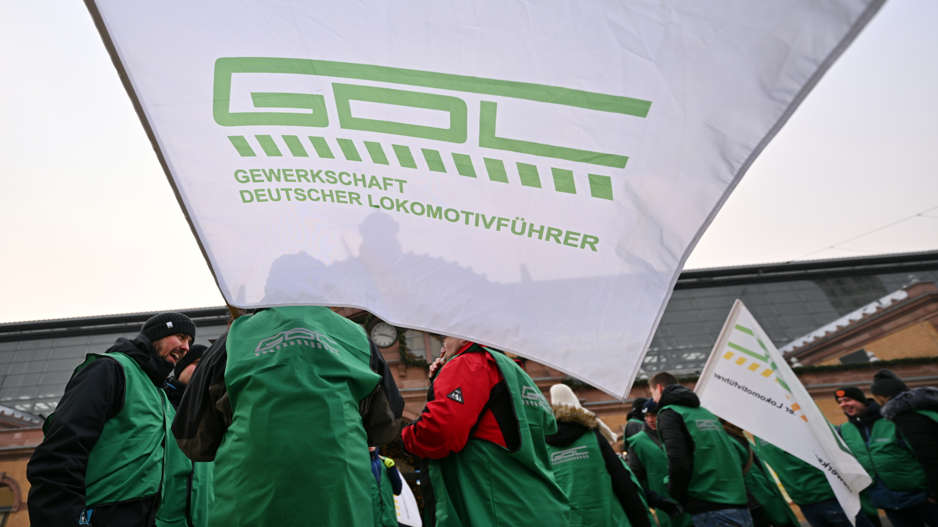 Mitglieder der Lokführergewerkschaft GDL stehen mit Fahnen vor dem Erfurter Hauptbahnhof
