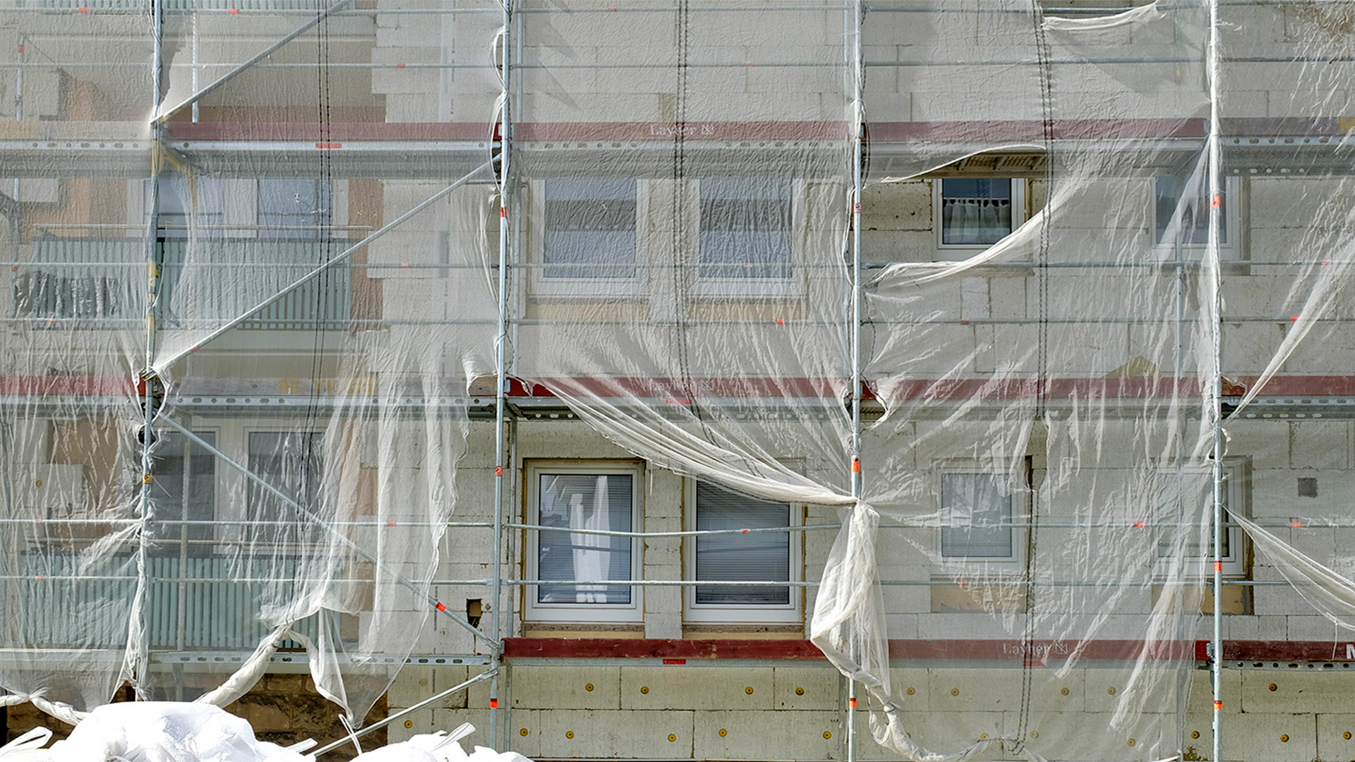 Ein eingerüstetes Haus. Hinter der Abdeckung vom Gerüst ist eine Erneuerung der Dämmung erkennbar | picture alliance / Uwe Zucchi
