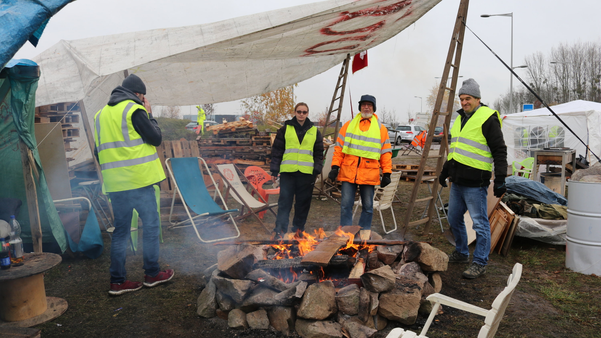 Vier "Gelbwesten" wärmen sich in ihrem Protestcamp nahe Straßburg an einem Lagerfeuer. (Archivbild vom 30. November) | Bildquelle: dpa