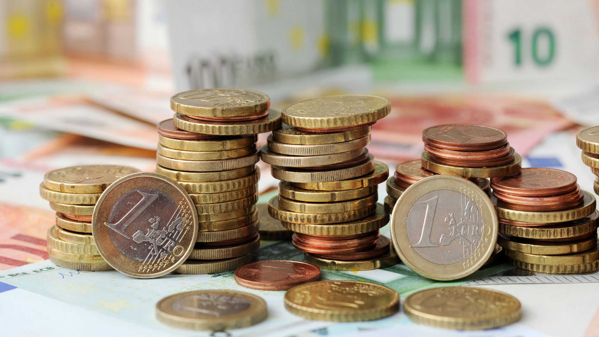 Euromünzen liegen gestapelt vor Banknoten