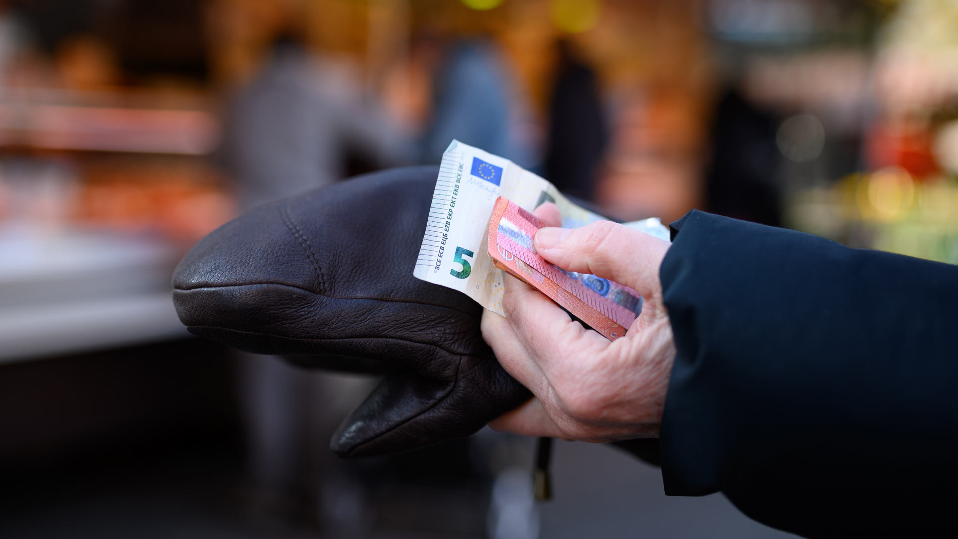 Eine Frau hält das Bargeld für ihren Einkauf in der Hand bereit. | picture alliance/dpa