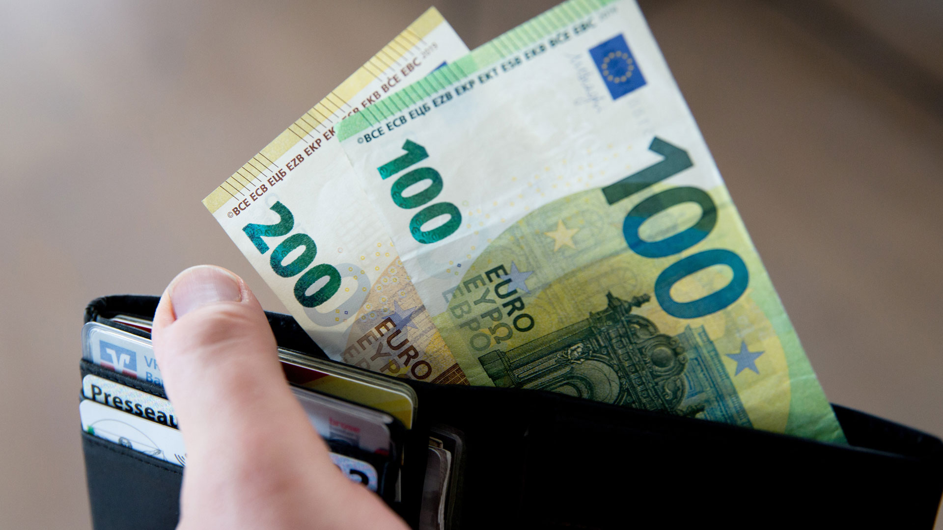 Aus einem Geldbeutel stehen 300 Euro in Bargeld heraus. | picture alliance / Fotostand