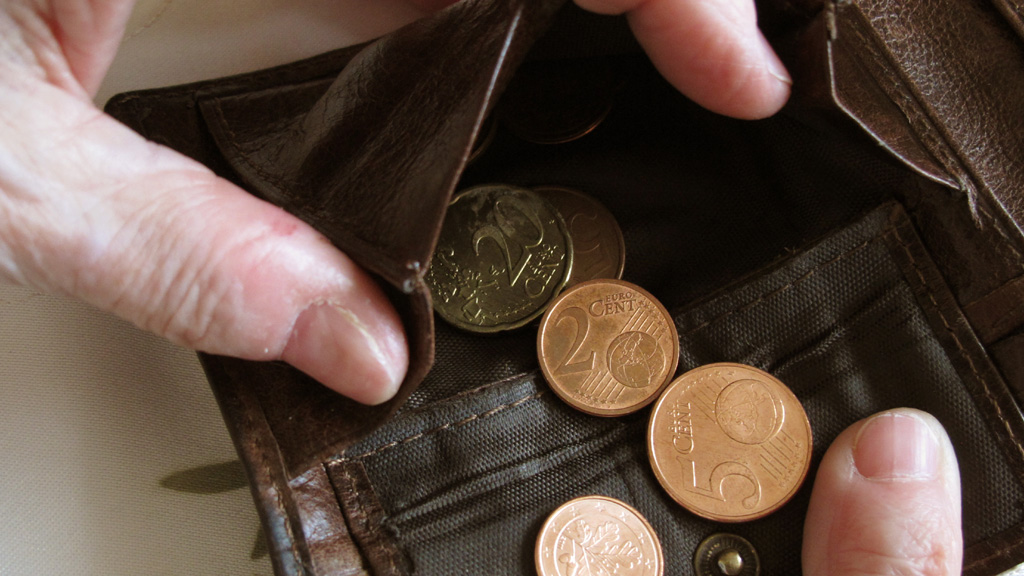 Eine Frau hält eine nahezu leere Geldbörse in den Händen | picture alliance / dpa