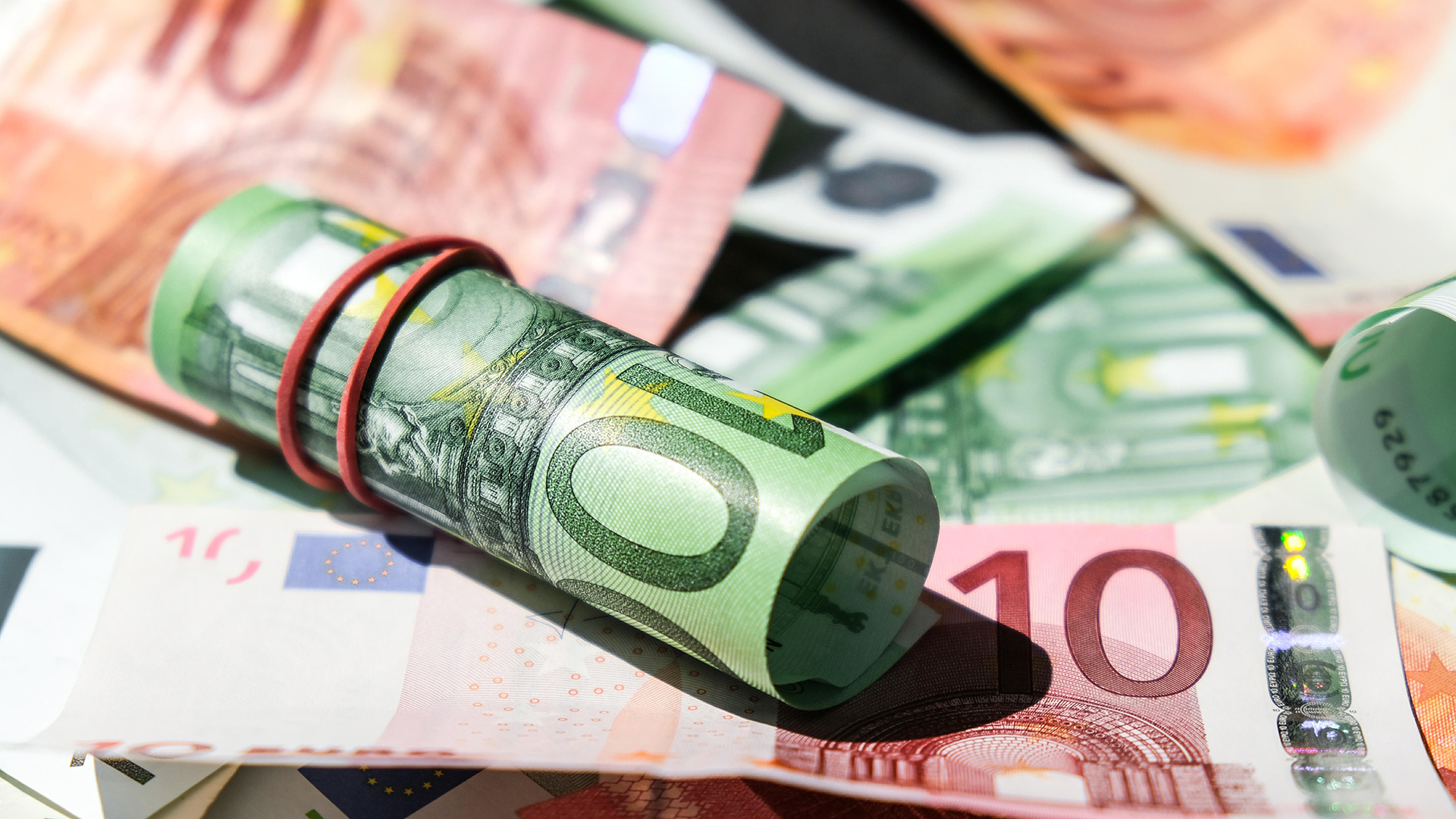 Ein aufgerollter Geldschein liegt auf Euroscheinen. | picture alliance / Zoonar