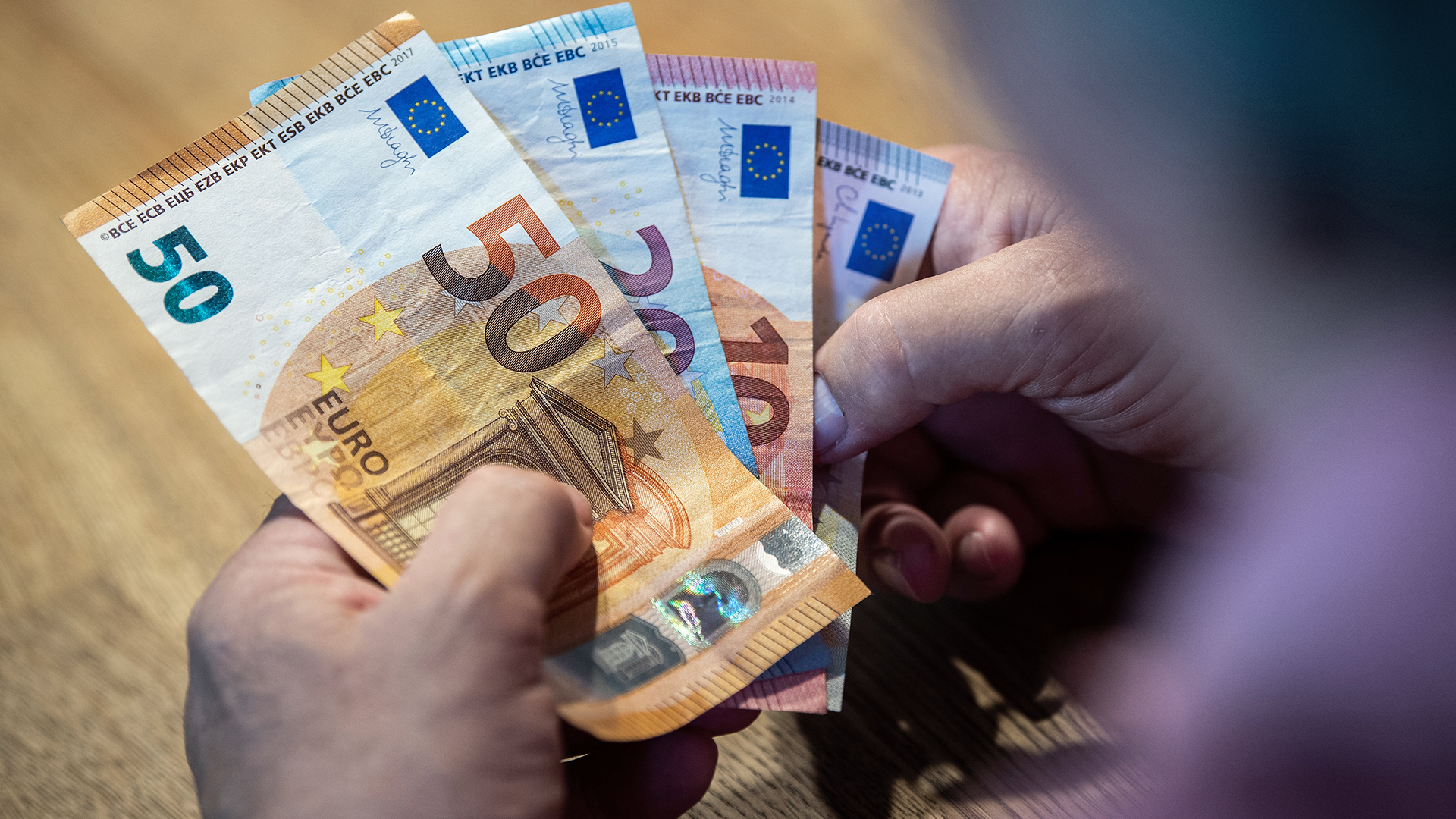 Hände halten Geldscheine (Euro). | picture alliance/dpa