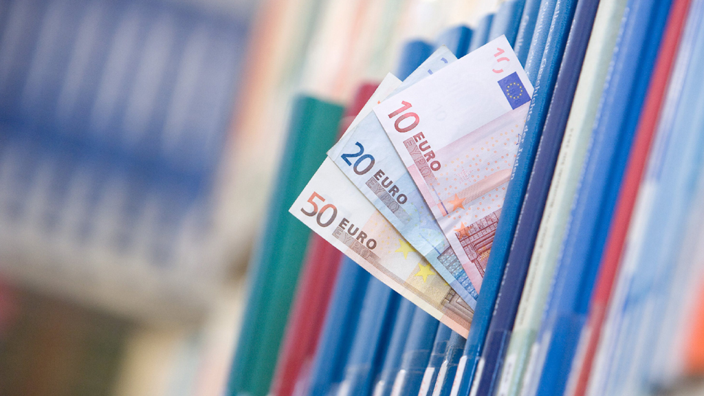 Drei Euro-Geldscheine schauen aus Büchern heraus