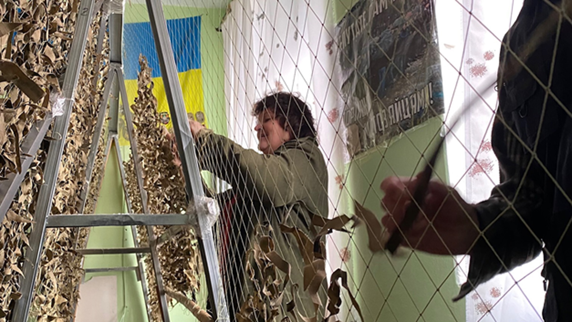 Vier Ehrenamtler eines ukrainischen Gemeindezentrums arbeiten an einem Tarnnetz. | WDR