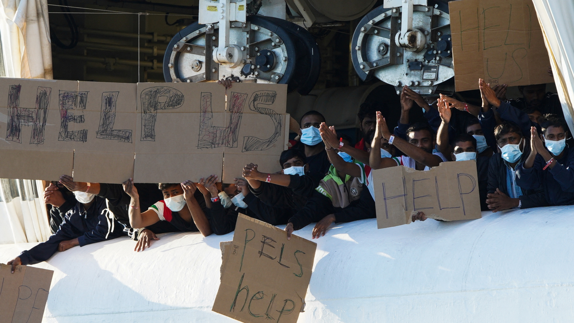 Gerettete Migranten an Bord der Geo Barrents halten Schilde hoch | REUTERS
