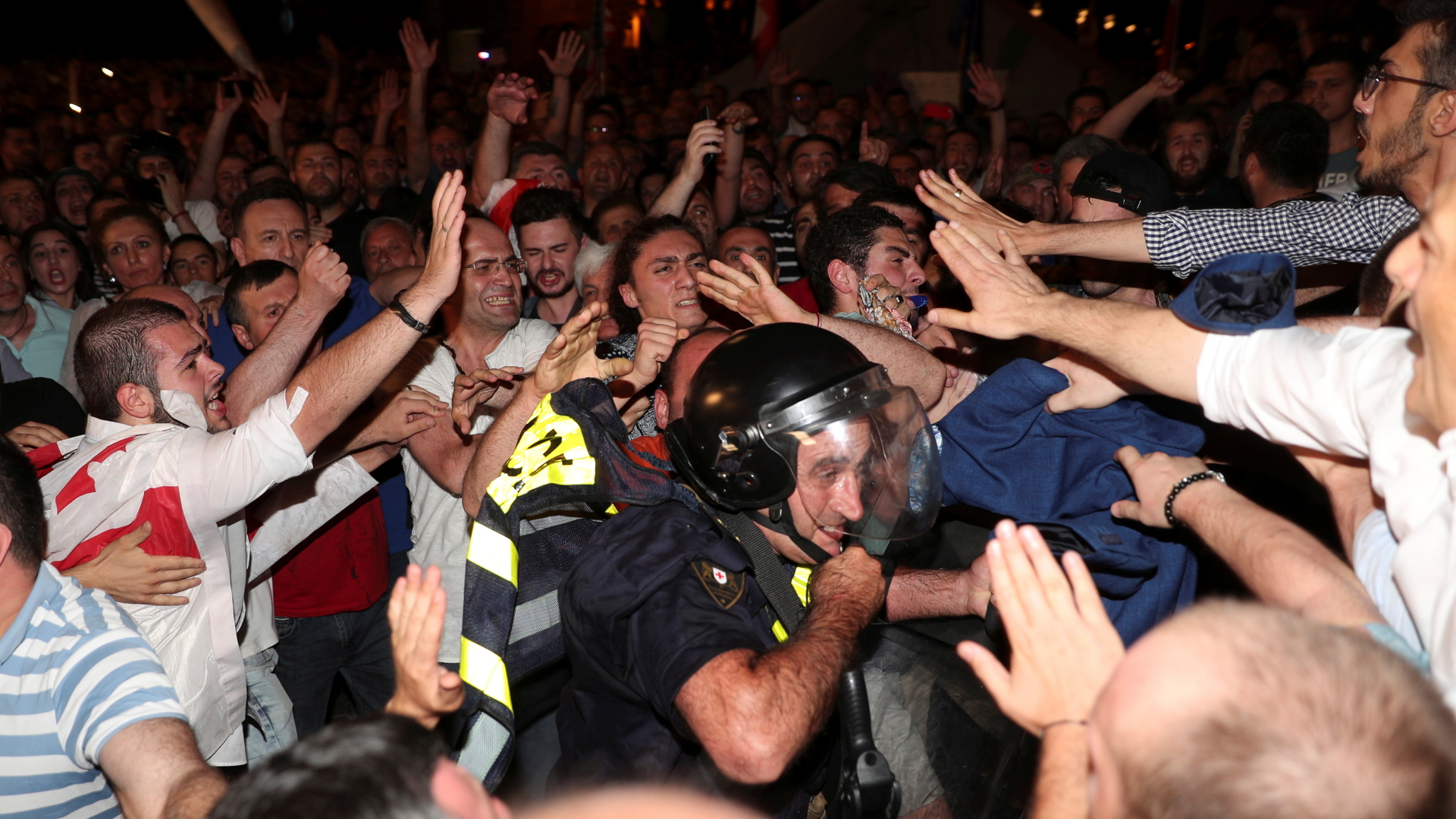 Ein Polizist zwischen Demonstranten in Georgien | Bildquelle: REUTERS