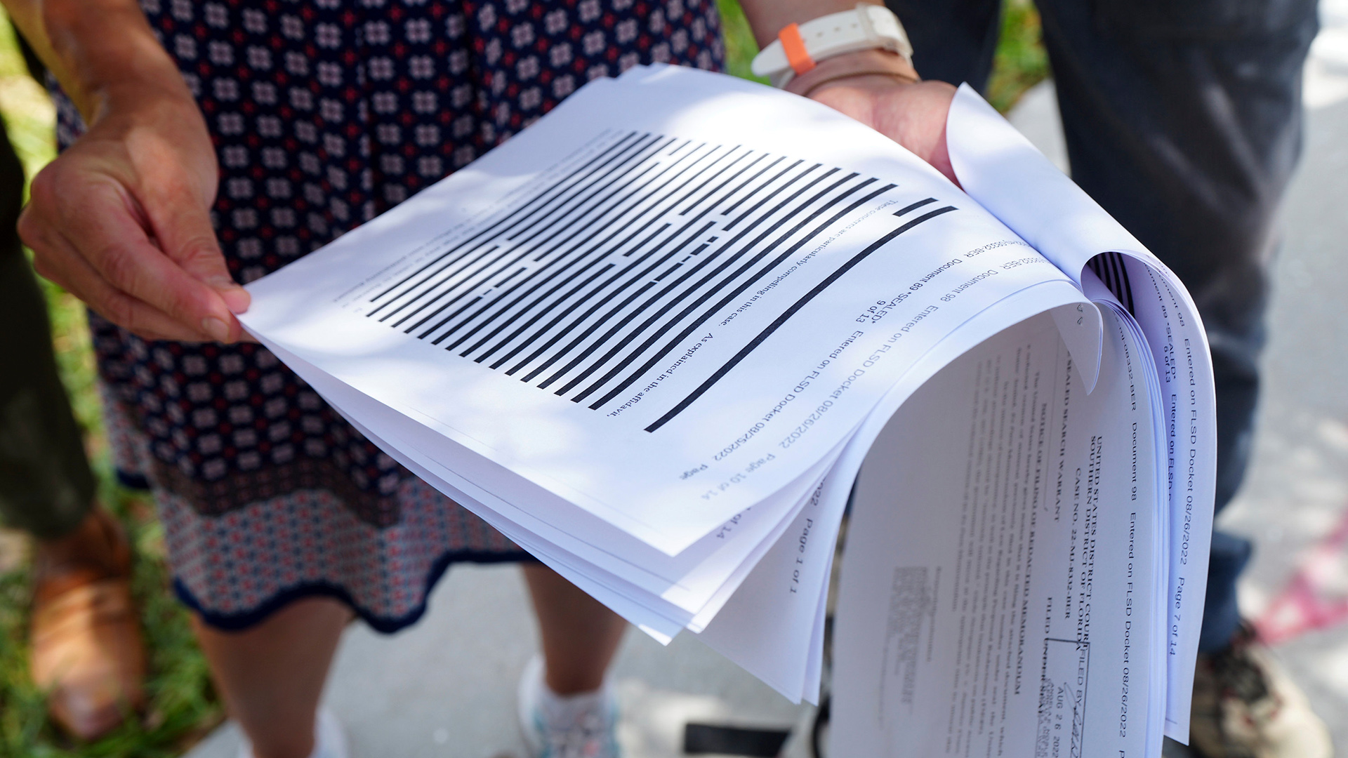 Eine Journalistin hält ein stark geschwärztes Dokument, das vom US-Justizministerium veröffentlicht wurde, in der Hand.