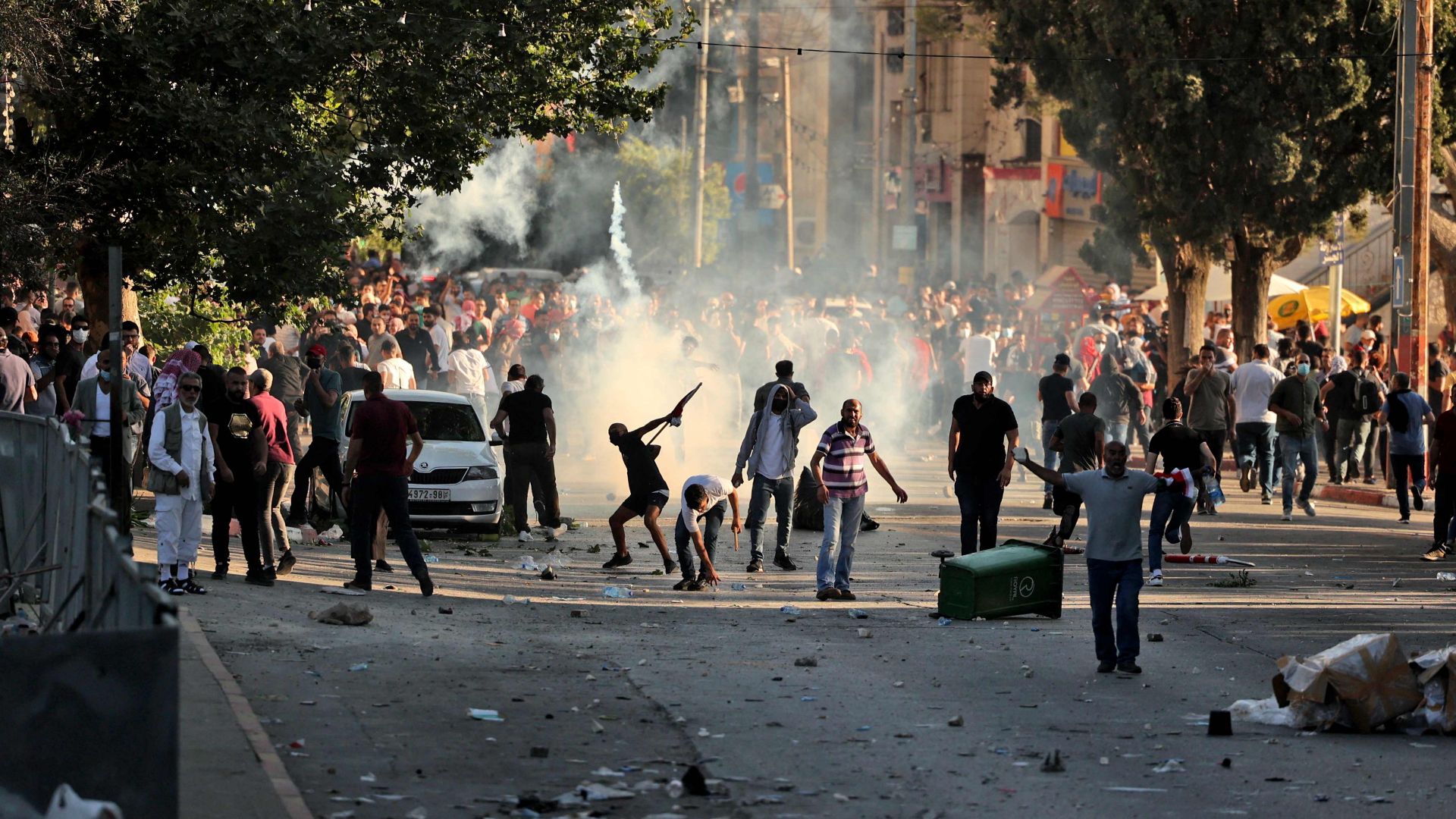 Bei Zusammenstößen von Demonstranten und Sicherheitskräften in Ramallah fliegen Steine, dazwischen steigen Tränengas-Wolken auf. | AFP