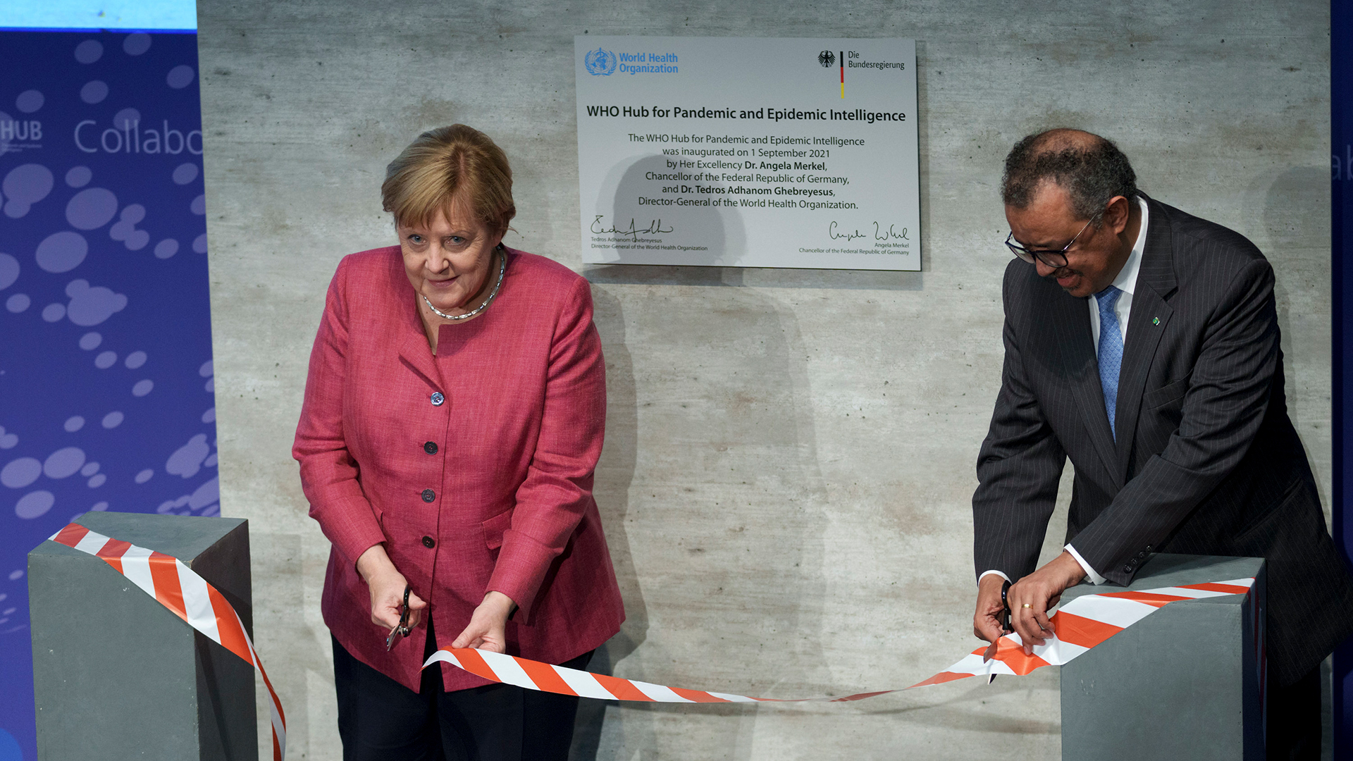 Tedros Adhanom Ghebreyesus und Angela Merkel zerschneiden bei der Eröffnungszeremonie des "WHO Hub for Pandemic and Epidemic Intelligence" im Langenbeck-Virchow-Gebäude in Berlin ein Band. | AP