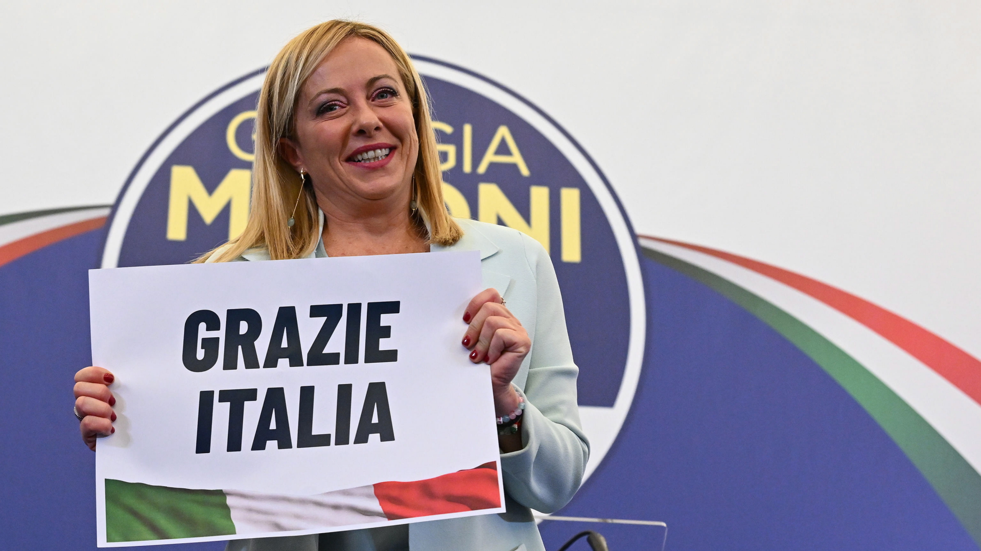 Giorgia Meloni hält ein Schild mit der Aufschrift: Grazie Italia