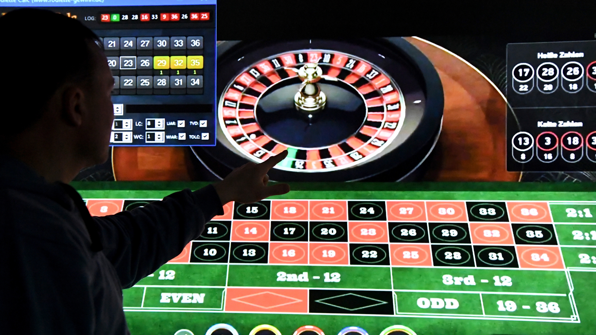 Ein Mann steht vor einem Bildschirm mit einem Online-Roulette-Spiel. 
