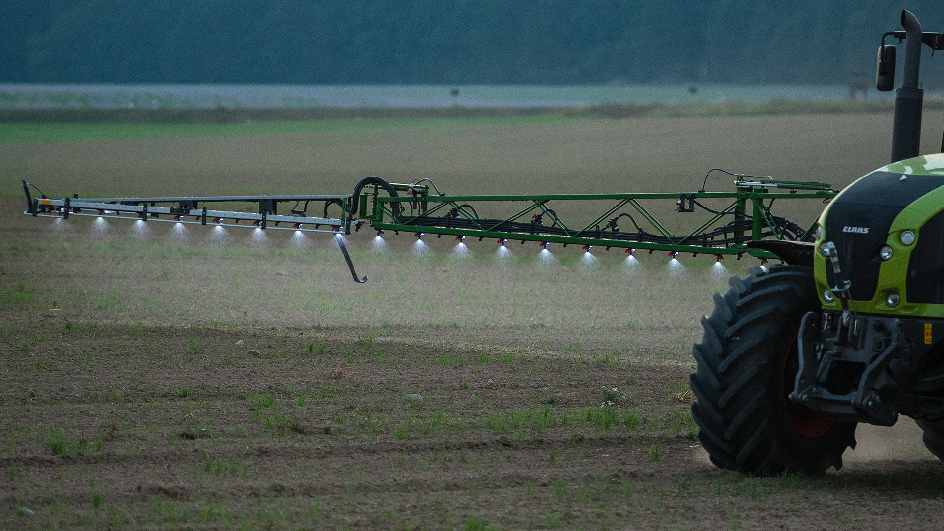 Ein Landwirt fährt mit einer Pestizid- und Düngerspritze über ein Feld