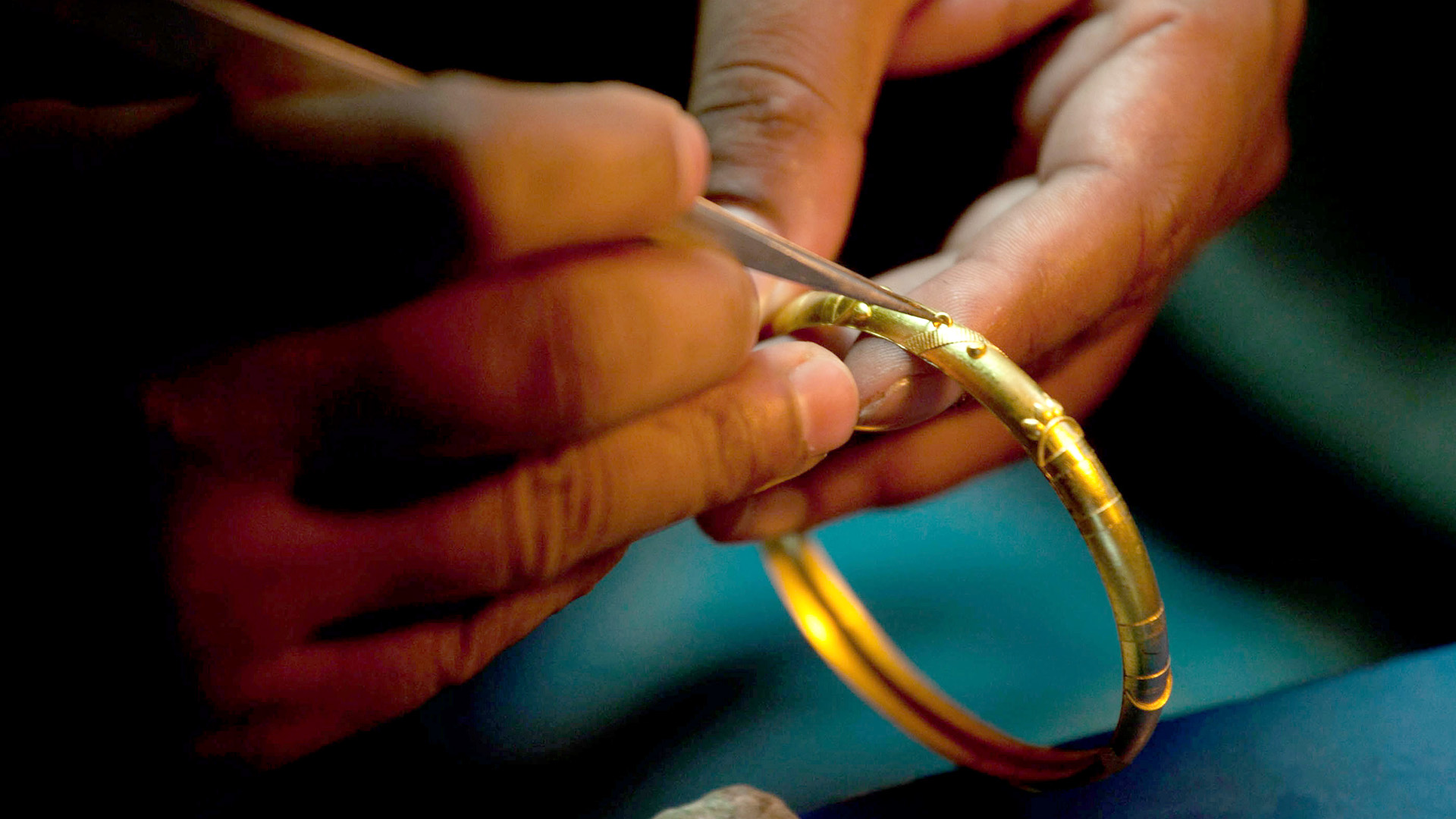 Hände untersuchen mit einer Pinzette einen Goldring | picture alliance / dpa
