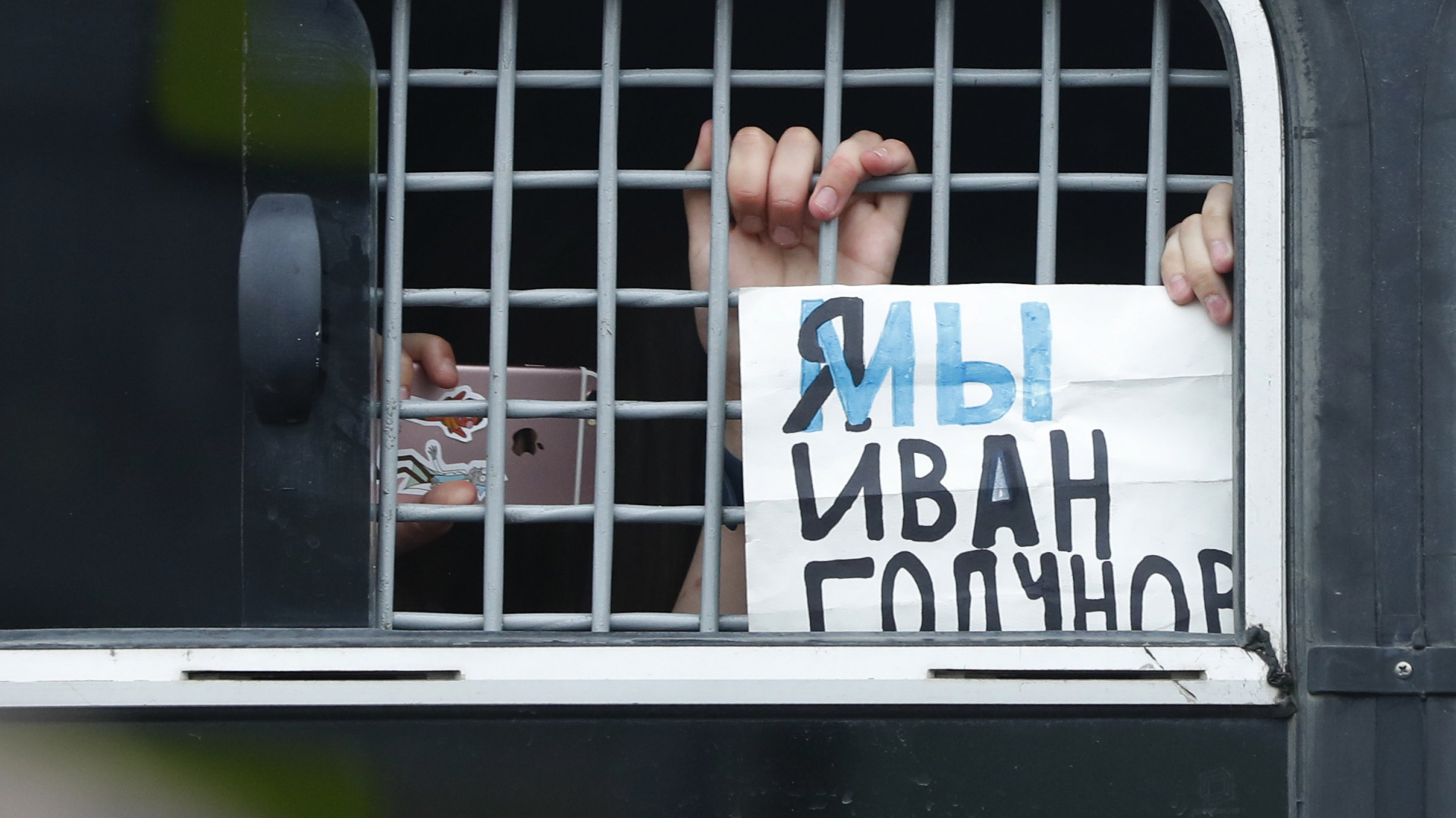 Ein festgenommener Demonstrant zeigt aus einem Polizeiwagen heraus ein Schild mit der Aufschrift: "Ich bin/Wir sind Iwan Golunow". Den Slogan hatten drei führende russische Zeitungen auf die Titelseiten genommen. | dpa