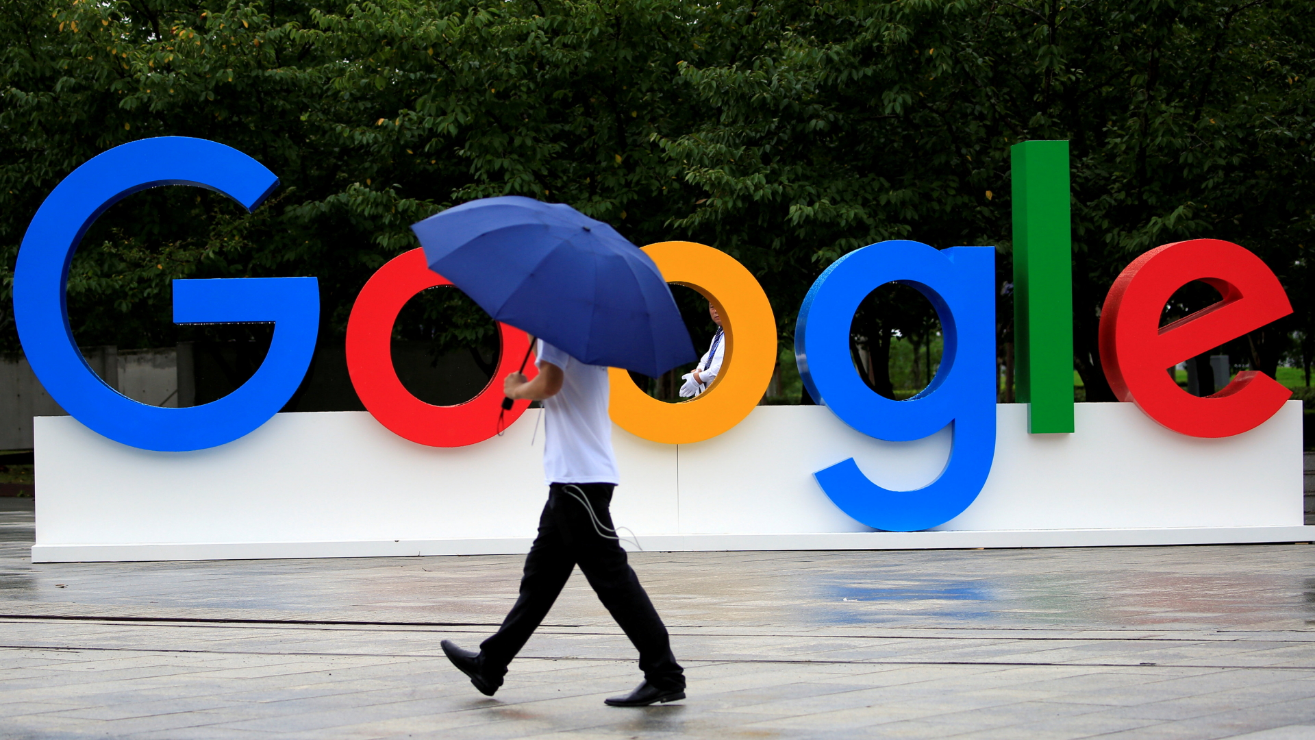 Ein Mann spaziert mit Regenschirm vor dem Google-Logo | Bildquelle: REUTERS