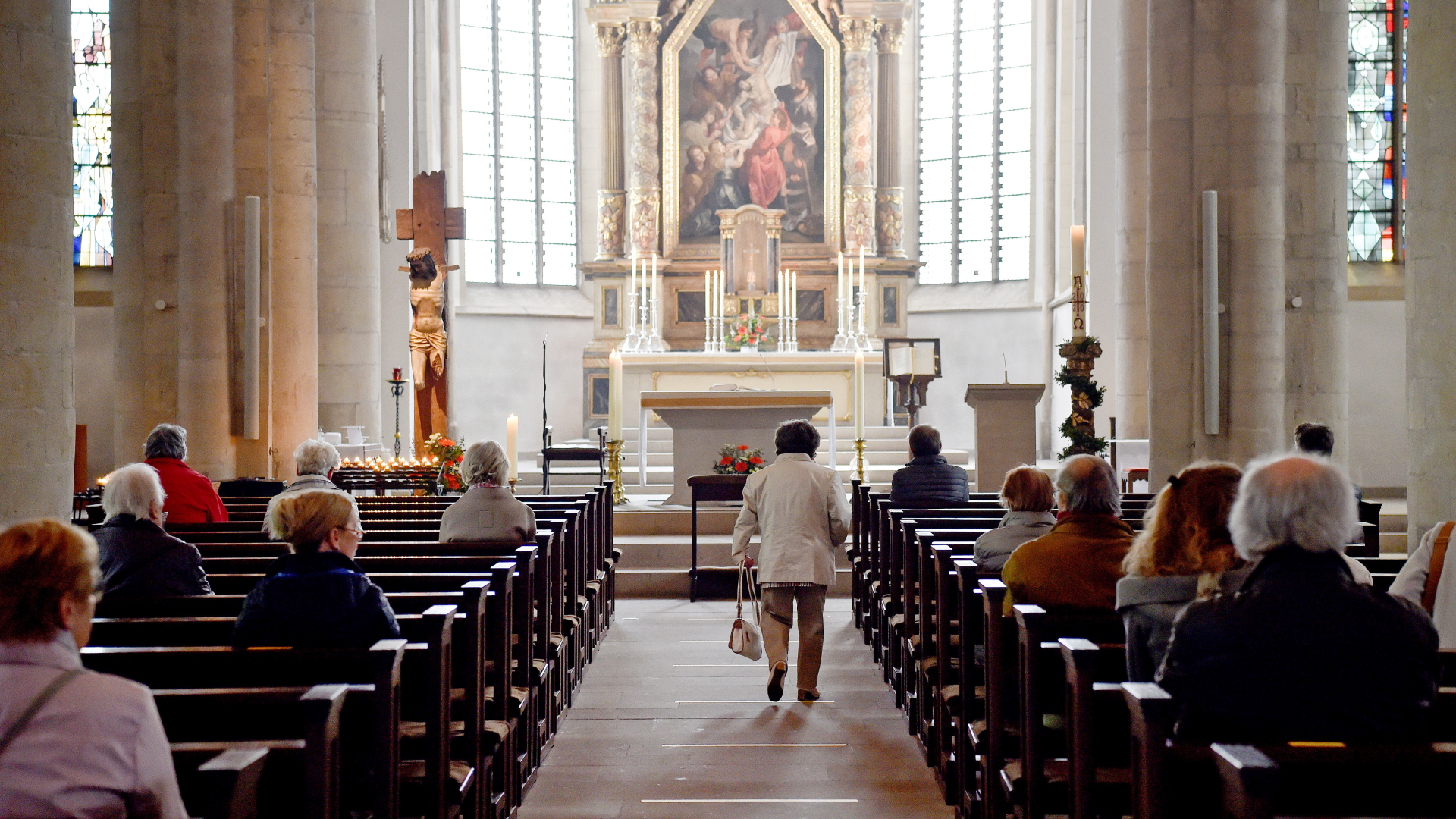 Eine Frau geht in einer Kirche in Recklinghausen über Markierungen auf dem Boden, die zur Einhaltung der Abstandsregelungen zum Schutz vor dem Coronavirus angebracht wurden.  | dpa