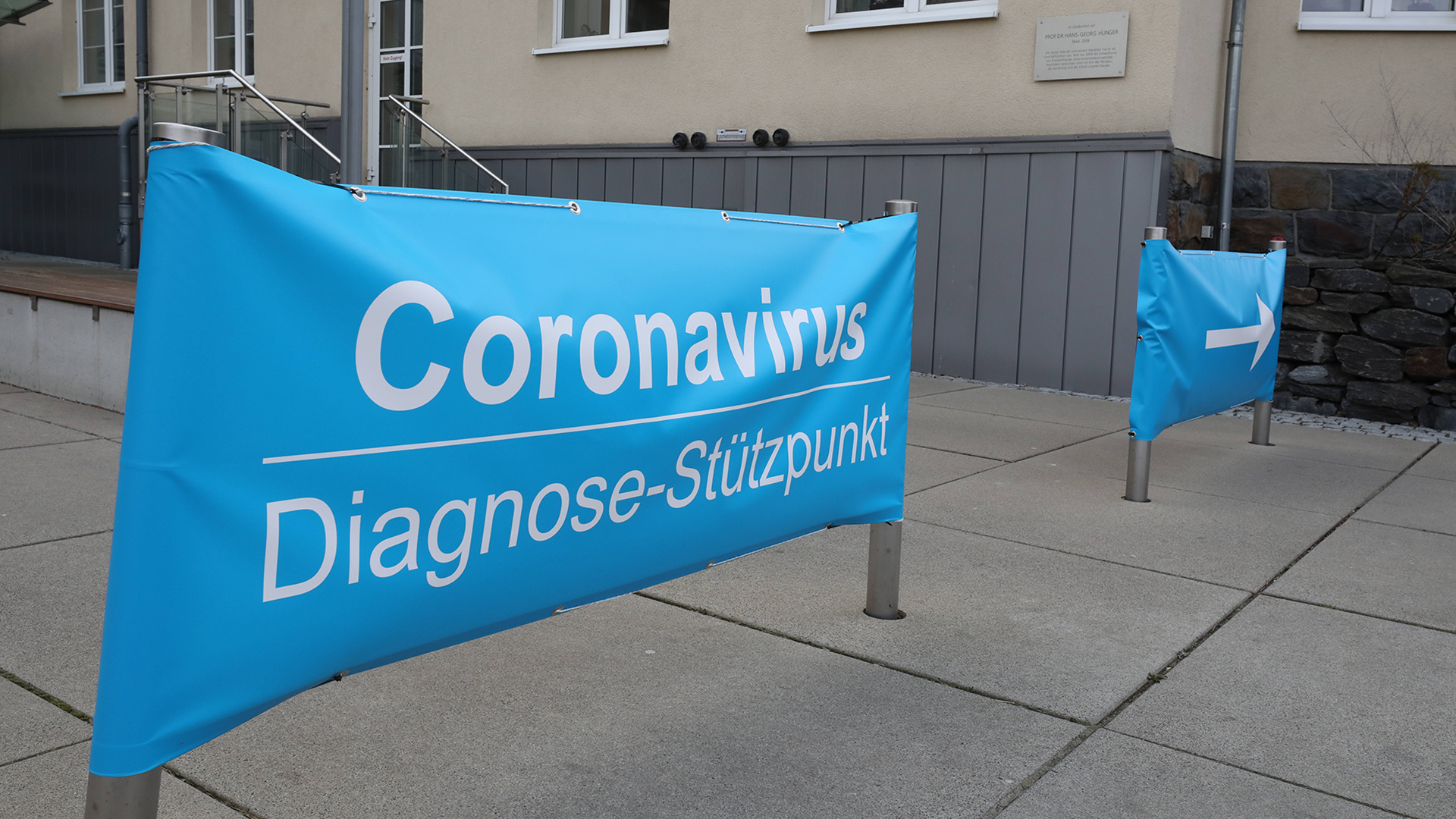 Ein improvisiertes Banner weist auf den  Coronavirus Diagnose-Stützpunkt am Eingang des Krankenhauses hin. | dpa