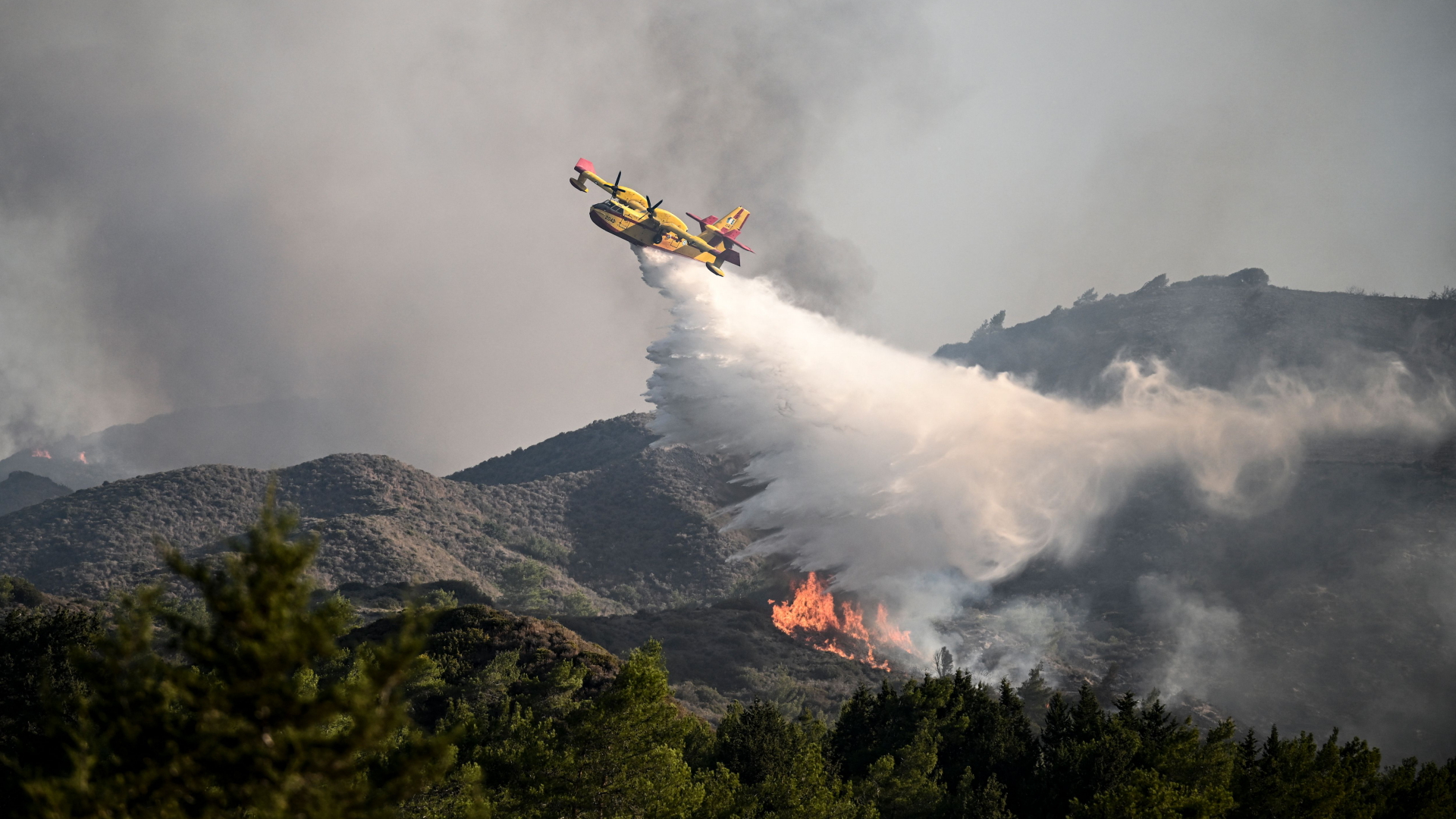 Ein Löschflugzeug wirft Wasser über einen Waldbrand in der Nähe des Dorfes Vati im südlichen Teil der griechischen Insel Rhodos