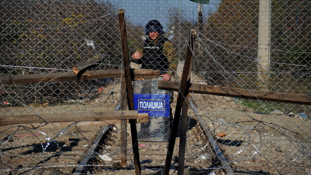 Ein Grenzkontrolleur steht hinter einem Stacheldrahtzaun an der griechischen Grenze. | null