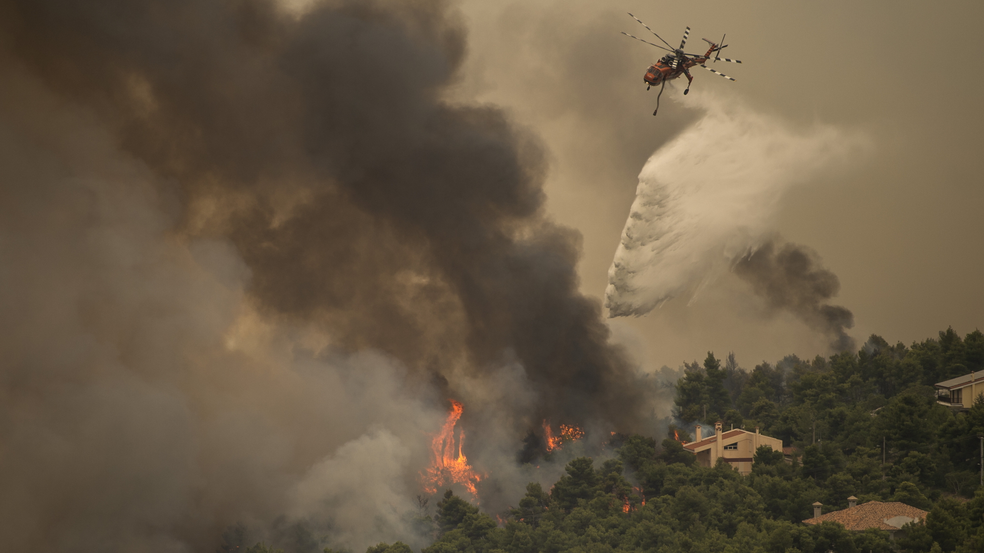 Ein Hubschrauber wirft in einem Waldgebiet nördlich von Athen Löschwasser ab | dpa