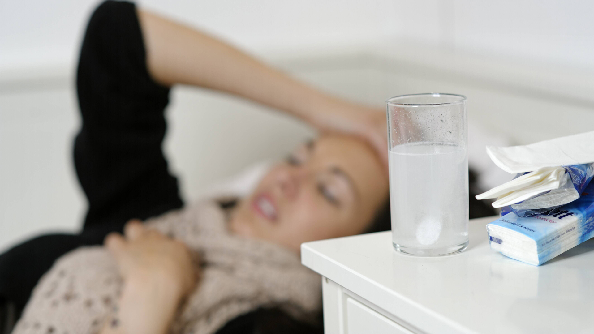 Eine junge Frau liegt mit einer Grippe im Bett. | imago stock&people