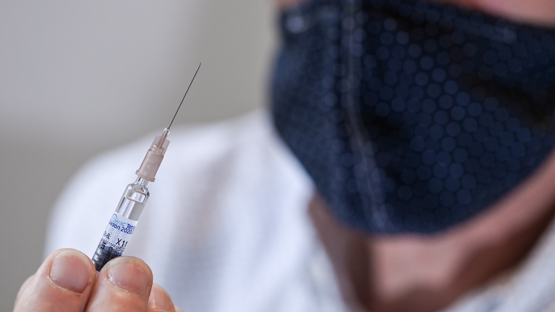 Ein Arzt hält während der Corona-Pandemie eine Spritze mit einer Grippeimpfung in der Hand. | dpa