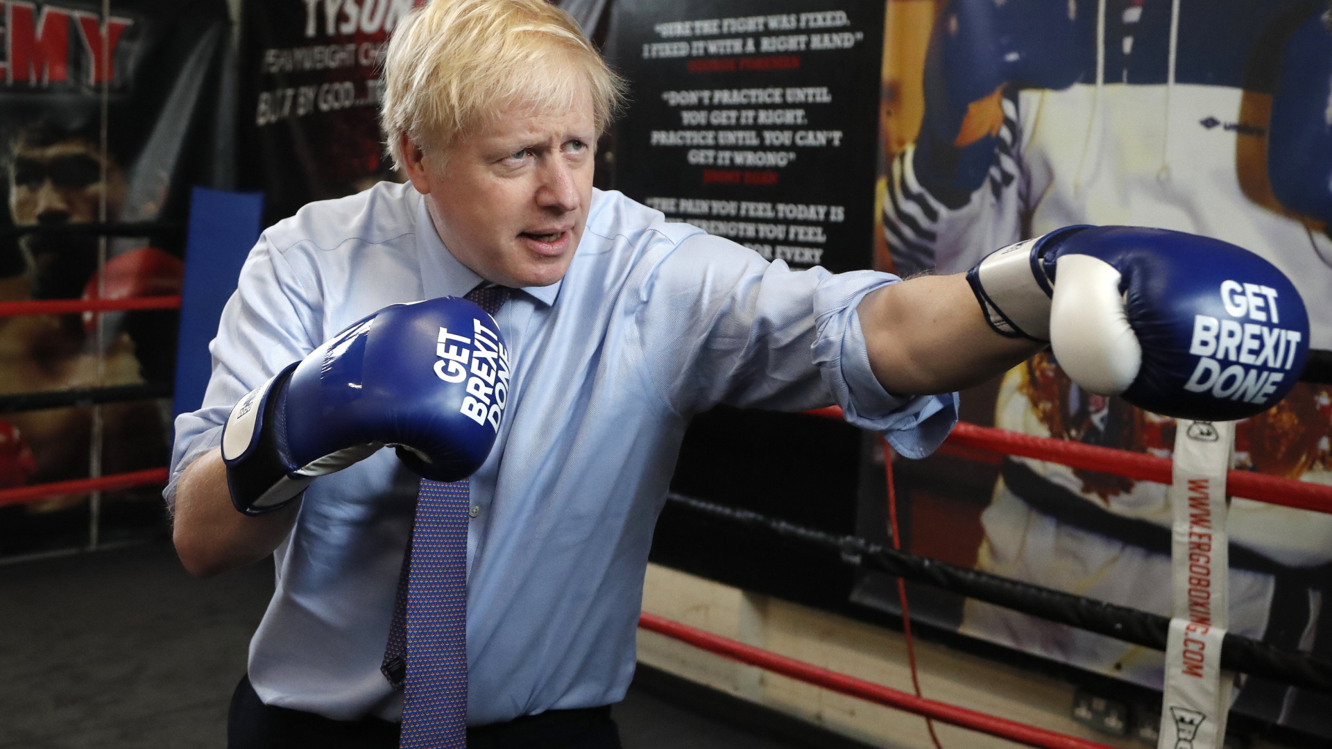 Großbritanniens Premier Boris Johnson mit Boxhandschuhen, auf die der Slogan "Get Brexit Done" gedruckt ist. | AP