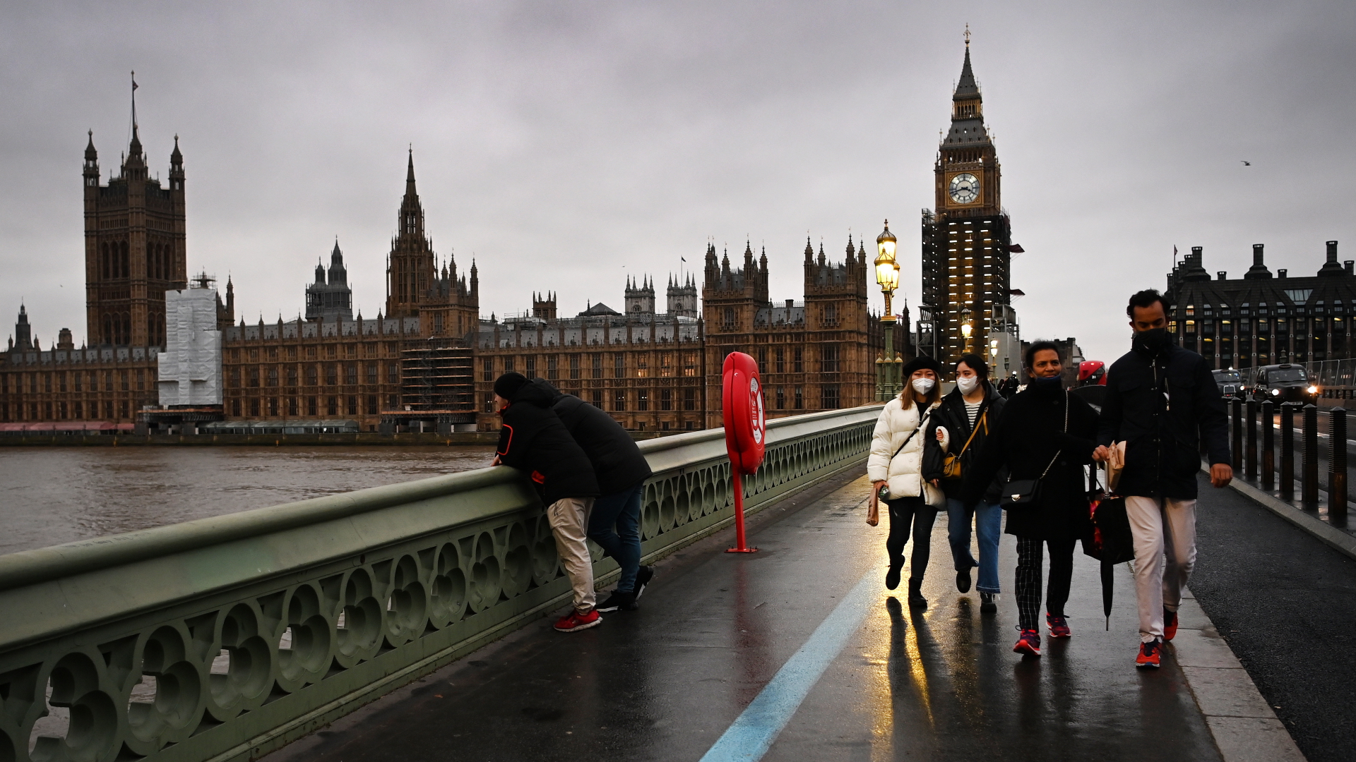 Fußgänger laufen nahe Big Ben in London über eine Brücke. Sie tragen Corona-Schutzmasken. | EPA