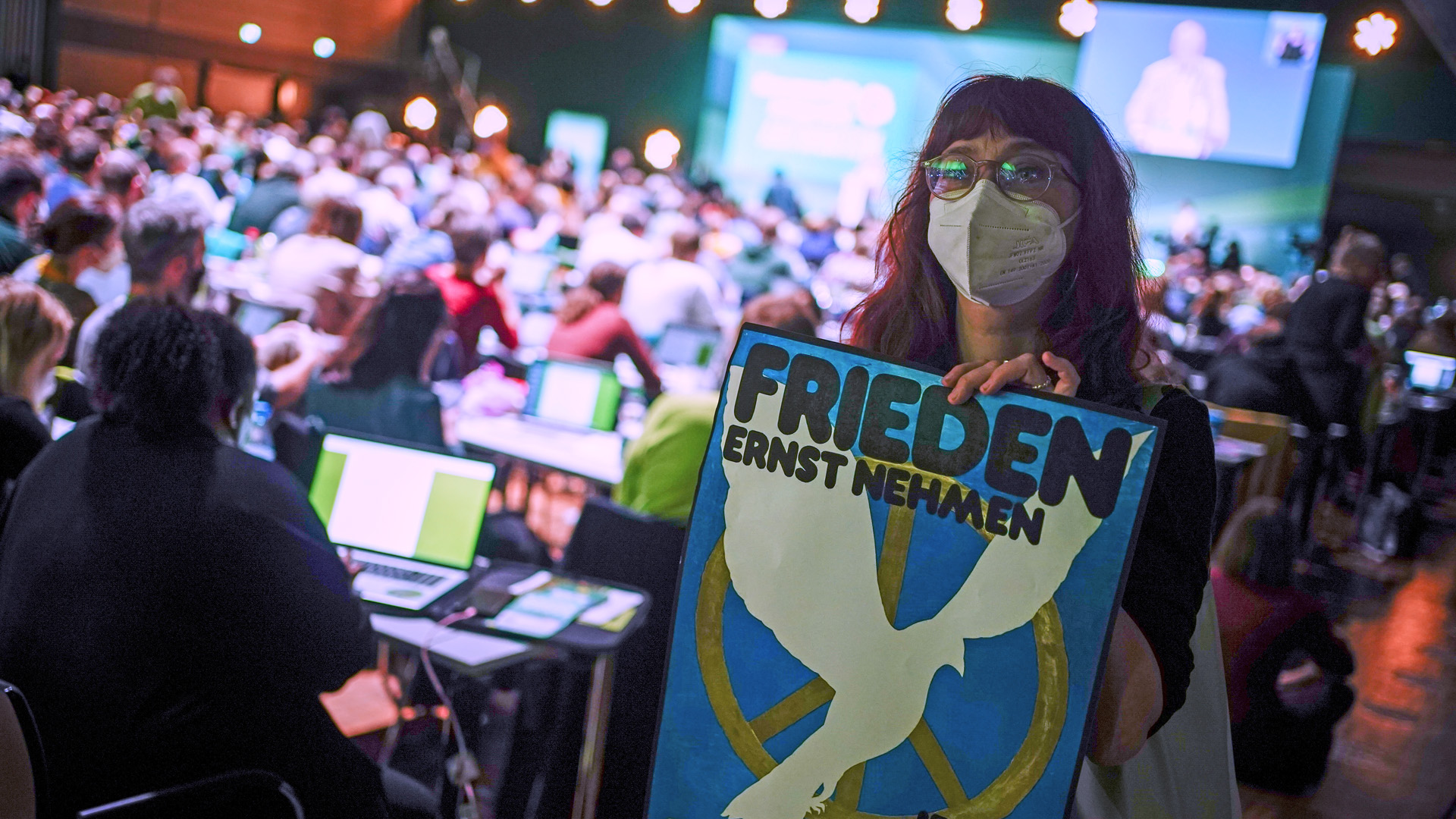 Eine Delegierte hält ein Plakat mit Forderung nach grüner Friedenspolitik auf der Bundesdelegiertenkonferenz in Bonn hoch