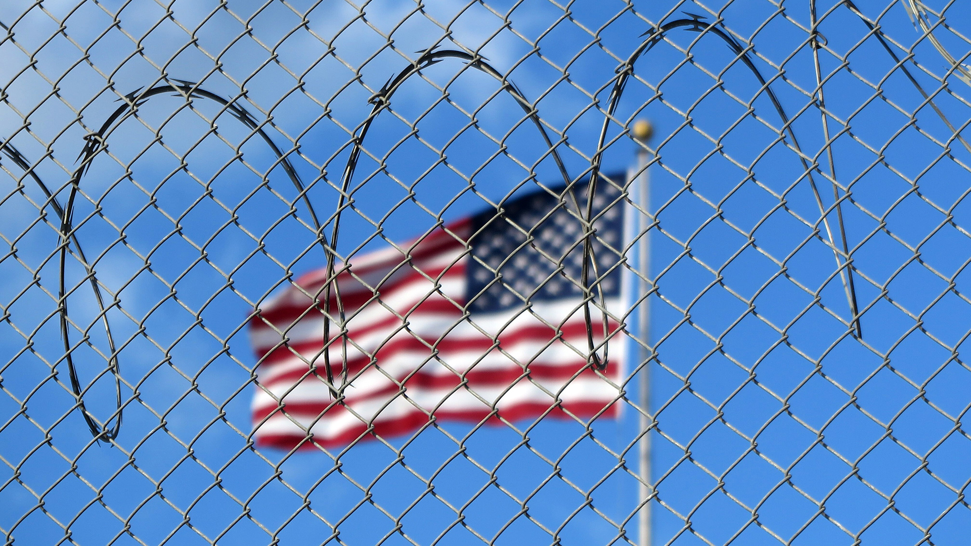 Eine US-Flagge weht hinter Stacheldraht auf dem Marinestützpunkt Guantánamo Bay auf Kuba.