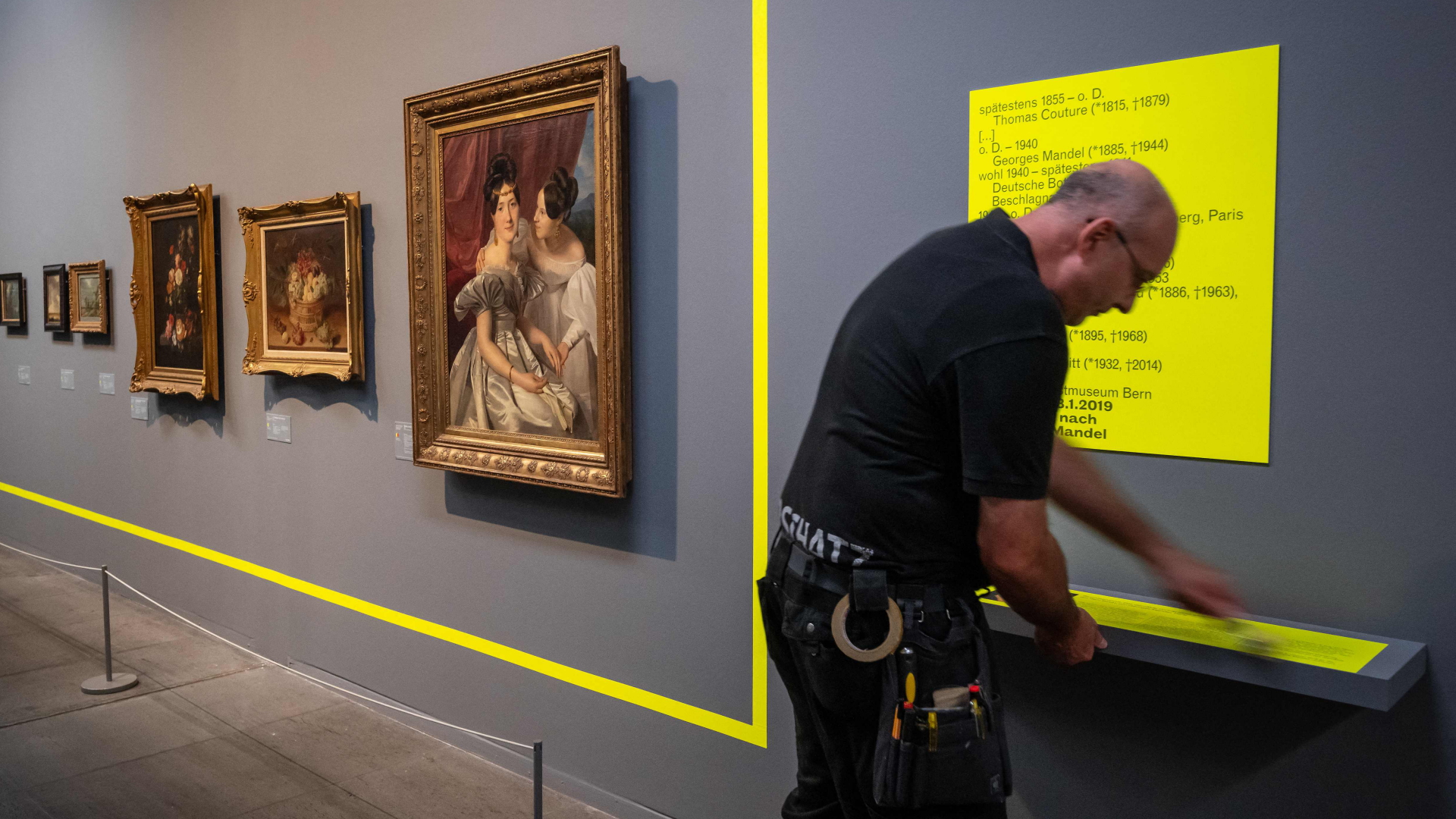 Ein Mitarbeiter bringt im Kunstmuseum Bern einen neongelben Rahmen an einer Wand neben Gemälden an. Der Rahmen verdeutlicht, dass einige Werke der Ausstellung "Gurlitt. Eine Bilanz" bereits an ihre rechtmäßigen Besitzer zurückgegeben wurden. | AFP