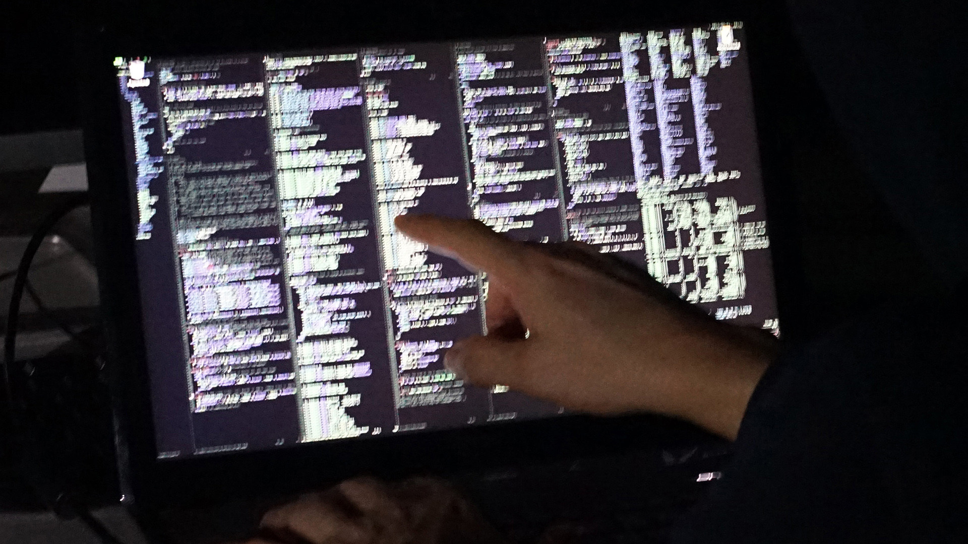Ein Mann sitzt vor einem Laptop und schaut sich einen Programmcode an.