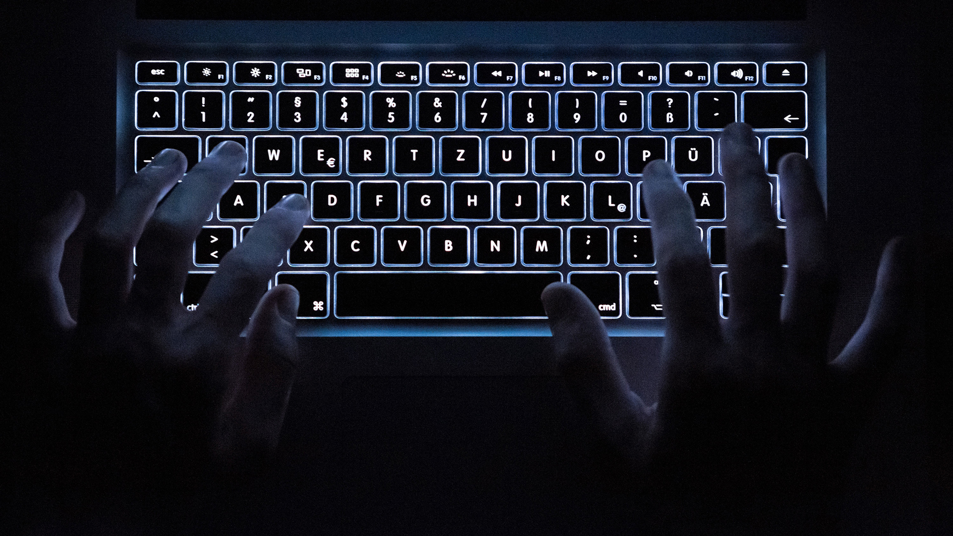 Ein Mann benutzt die beleuchtete Tastatur eines Notebooks. | dpa