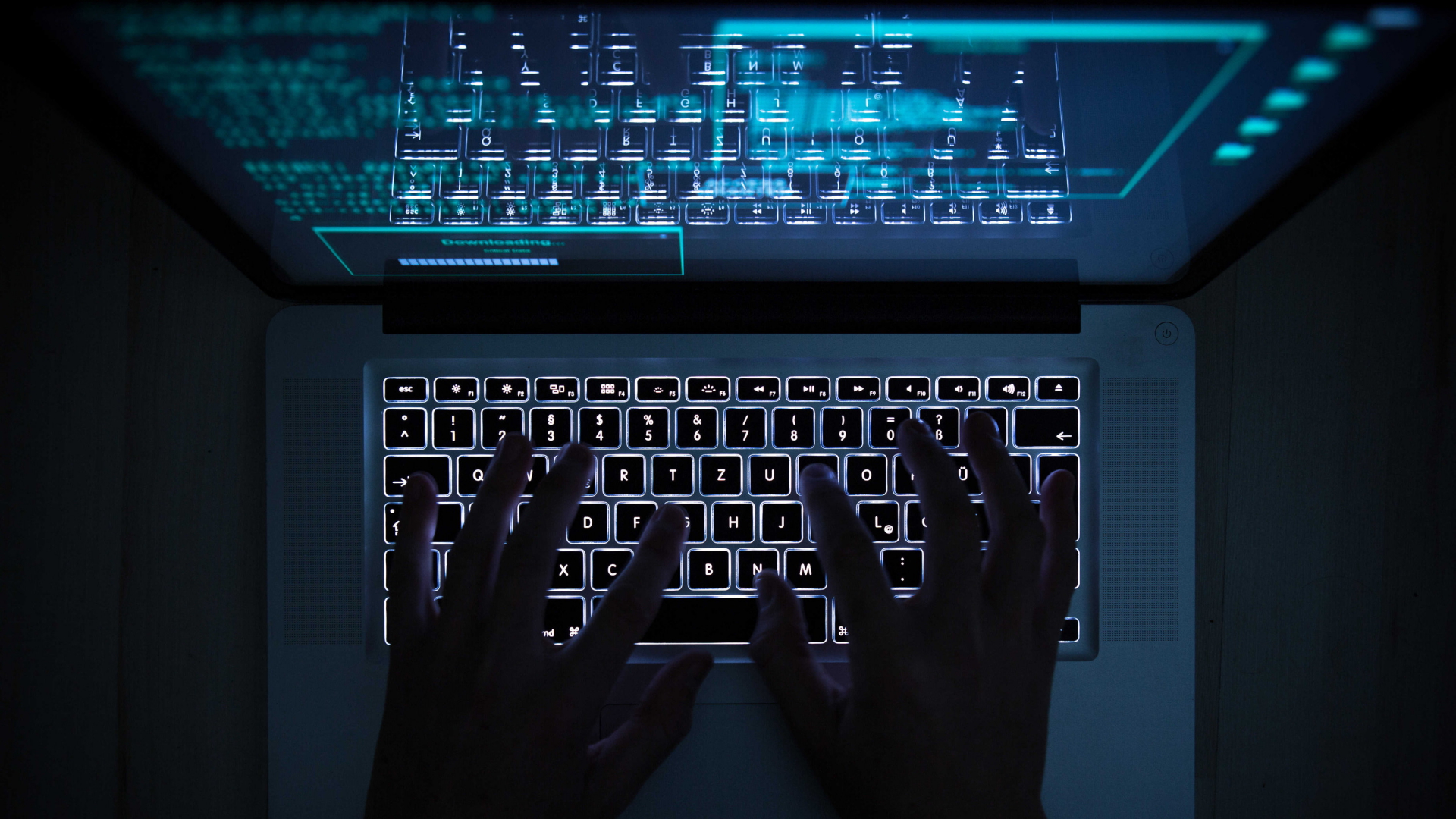 Eine Person bedient die beleuchtete Tastatur eines Laptops. Auf dem Monitor ist ein Hacker-Programm geöffnet. | dpa
