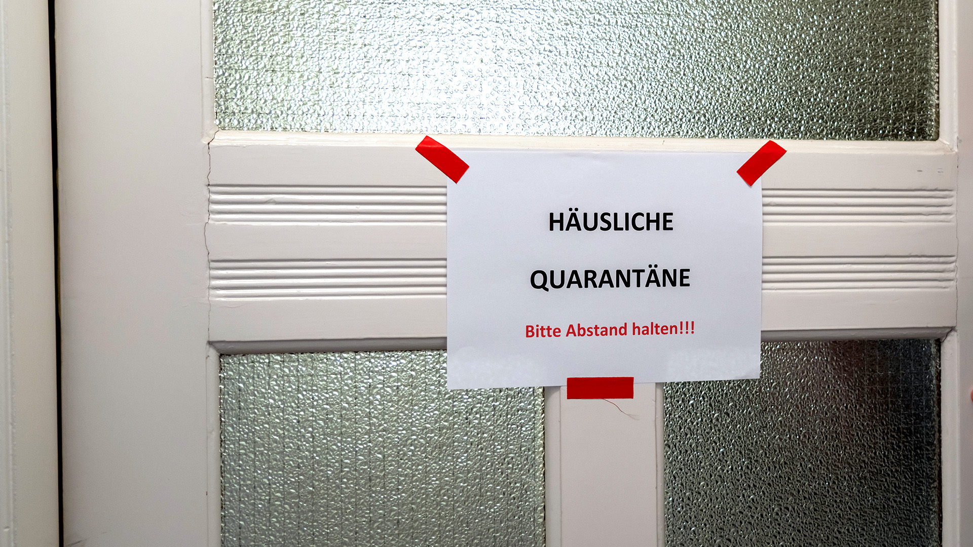 Ein Zettel mit der Aufschrift "Häusliche Quarantäne Bitte Abstand halten!!!" hängt an einer Tür