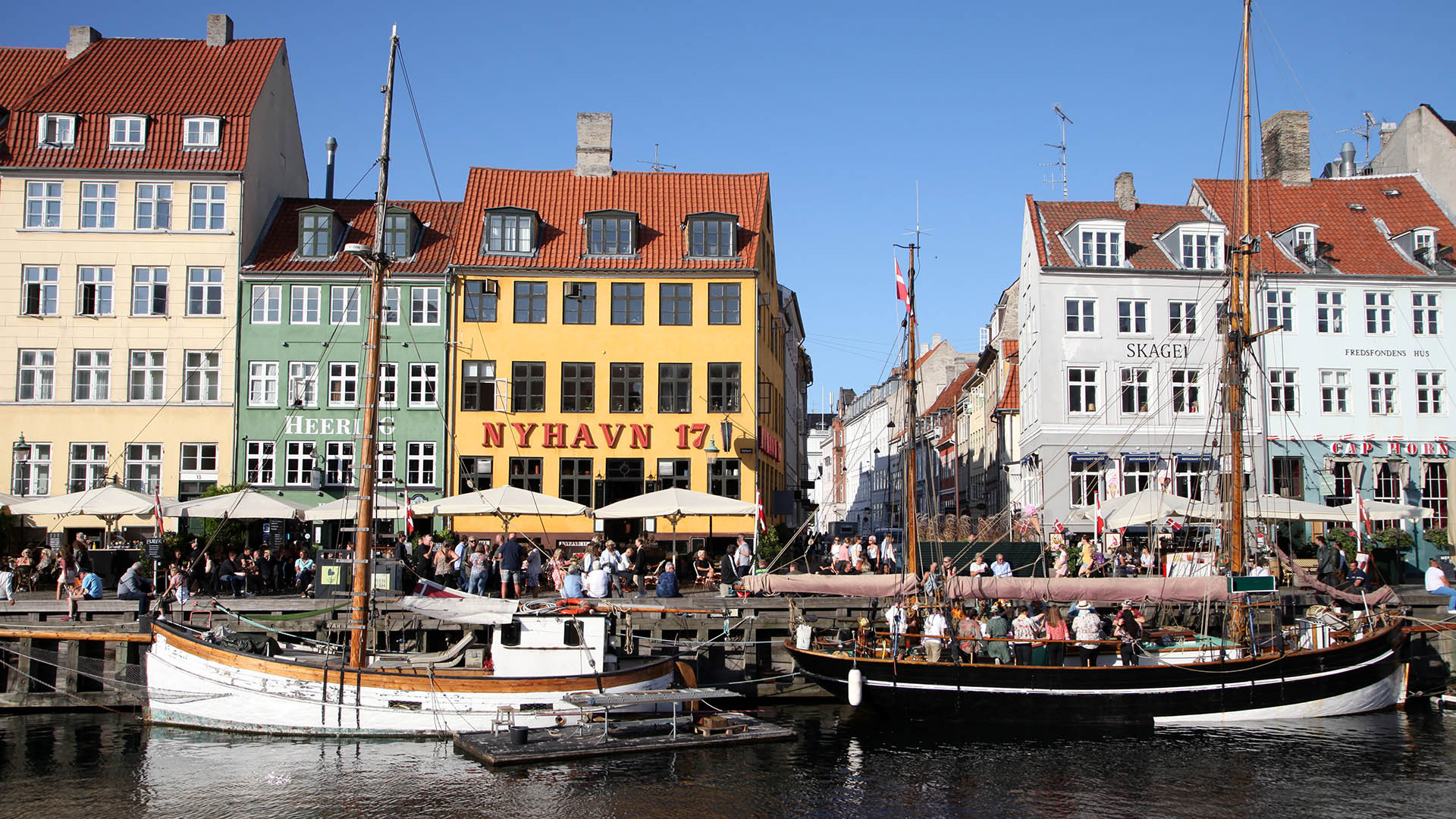 Passanten spazieren am kopenhagener Nyhavn entlang.