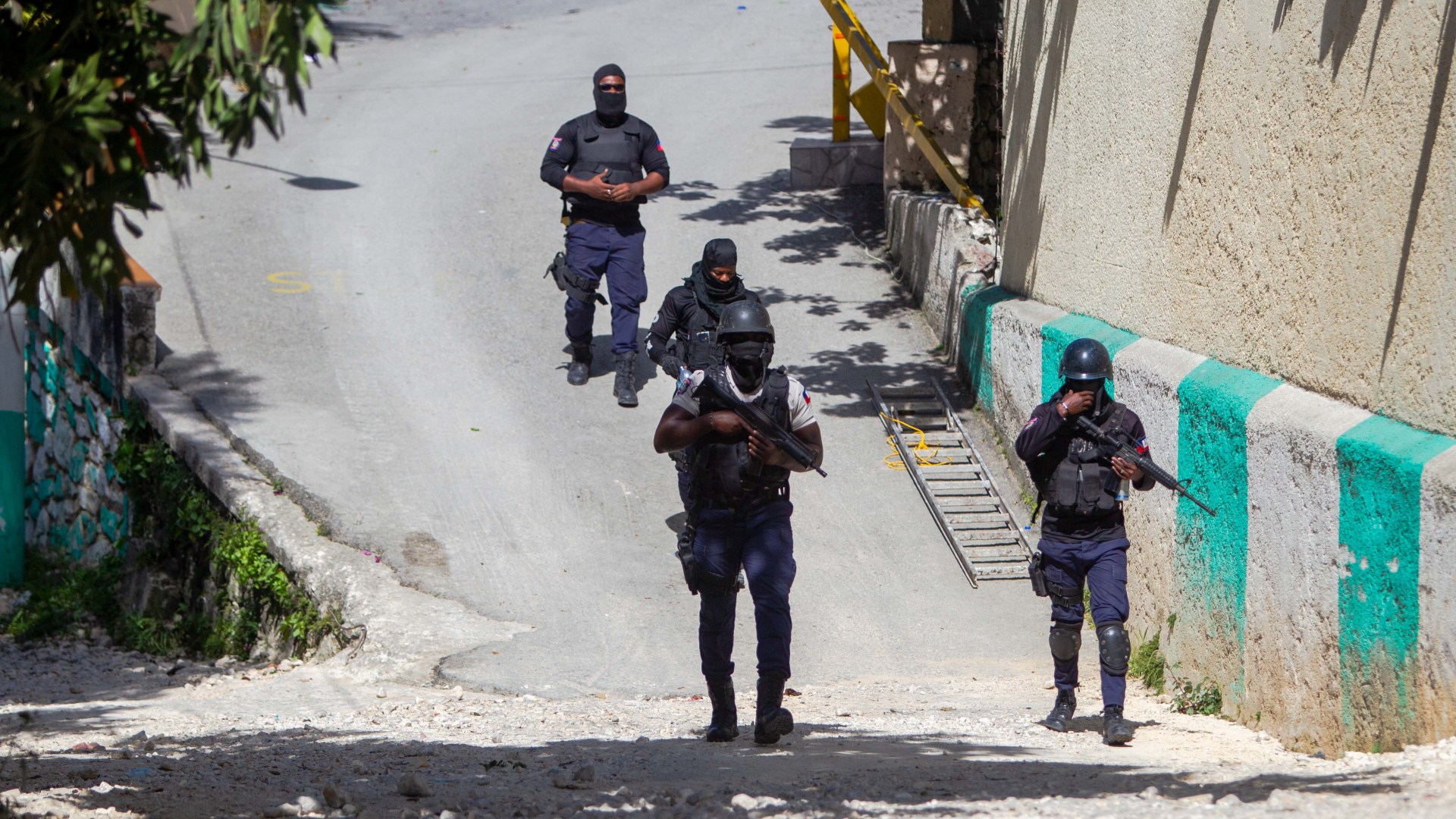 Haitianische Polizisten gehen bewaffnet eine Straße entlang. | EPA