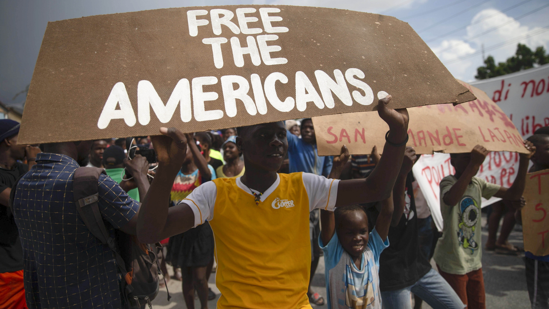 "Free the Americans" (Befreit die Amerikaner), steht auf dem Plakat, das ein Junge während einer Kundgebung nach der Entführung von Missionaren hoch hält. | dpa